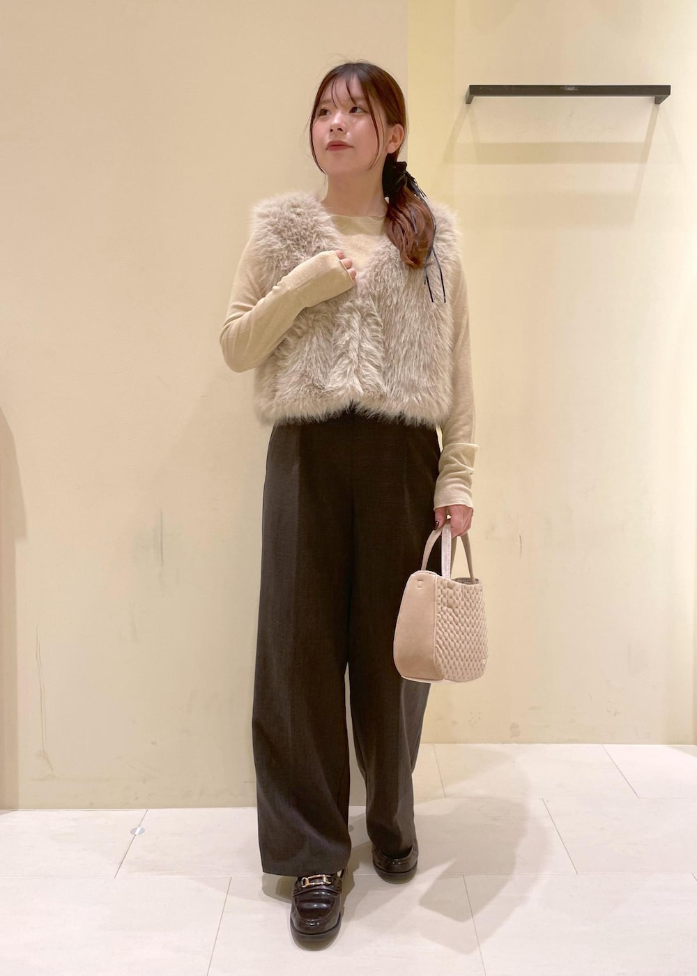 ブラック系のスラックス、ベージュ系のTシャツ/カットソー、ベージュ系のベストを着用したレディースの秋コーディネートの4枚目の写真