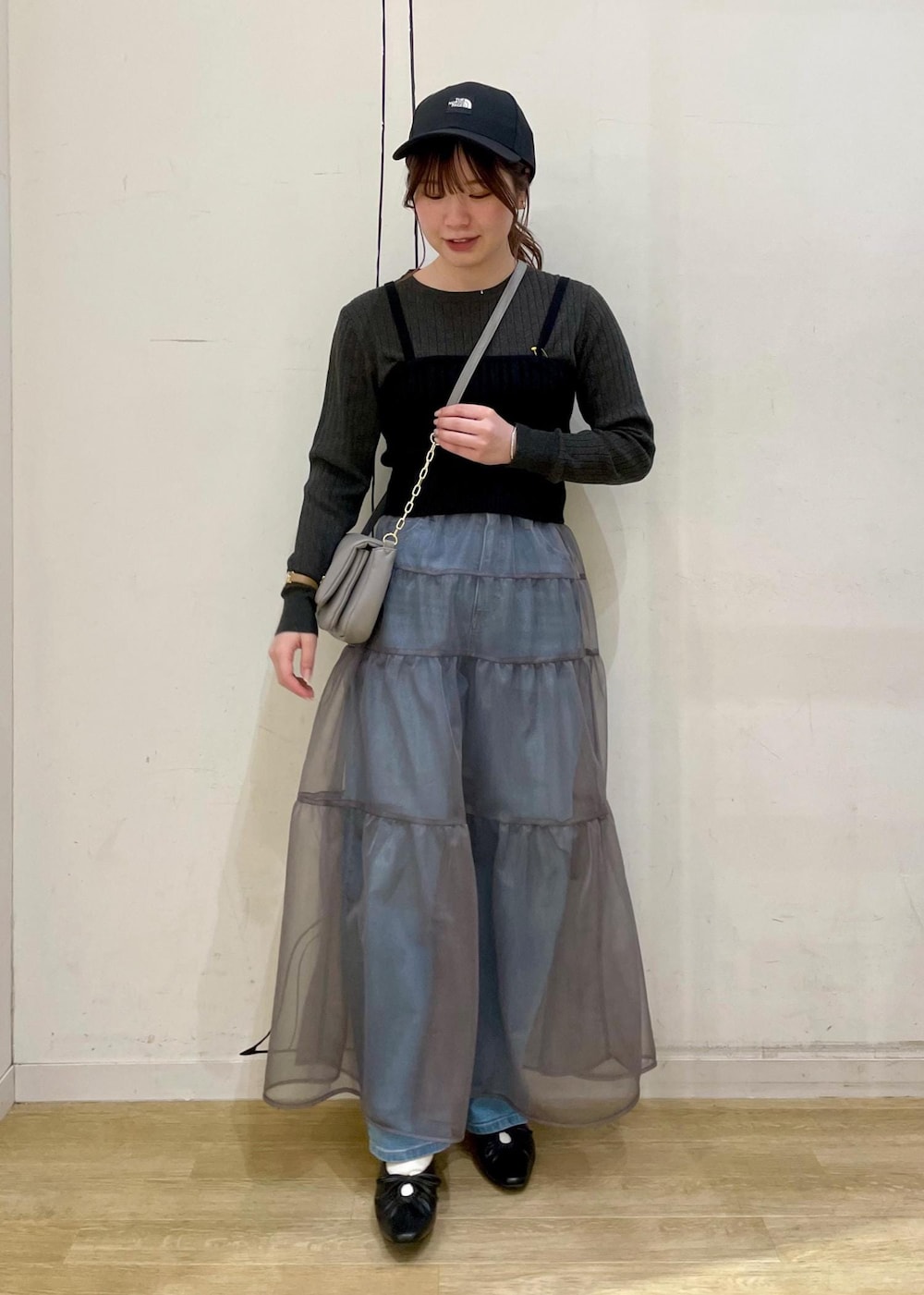 グレー系のショルダーバッグ、ブラック系のベスト、グレー系のニット/セーターを着用したレディースの春コーディネートの3枚目の写真