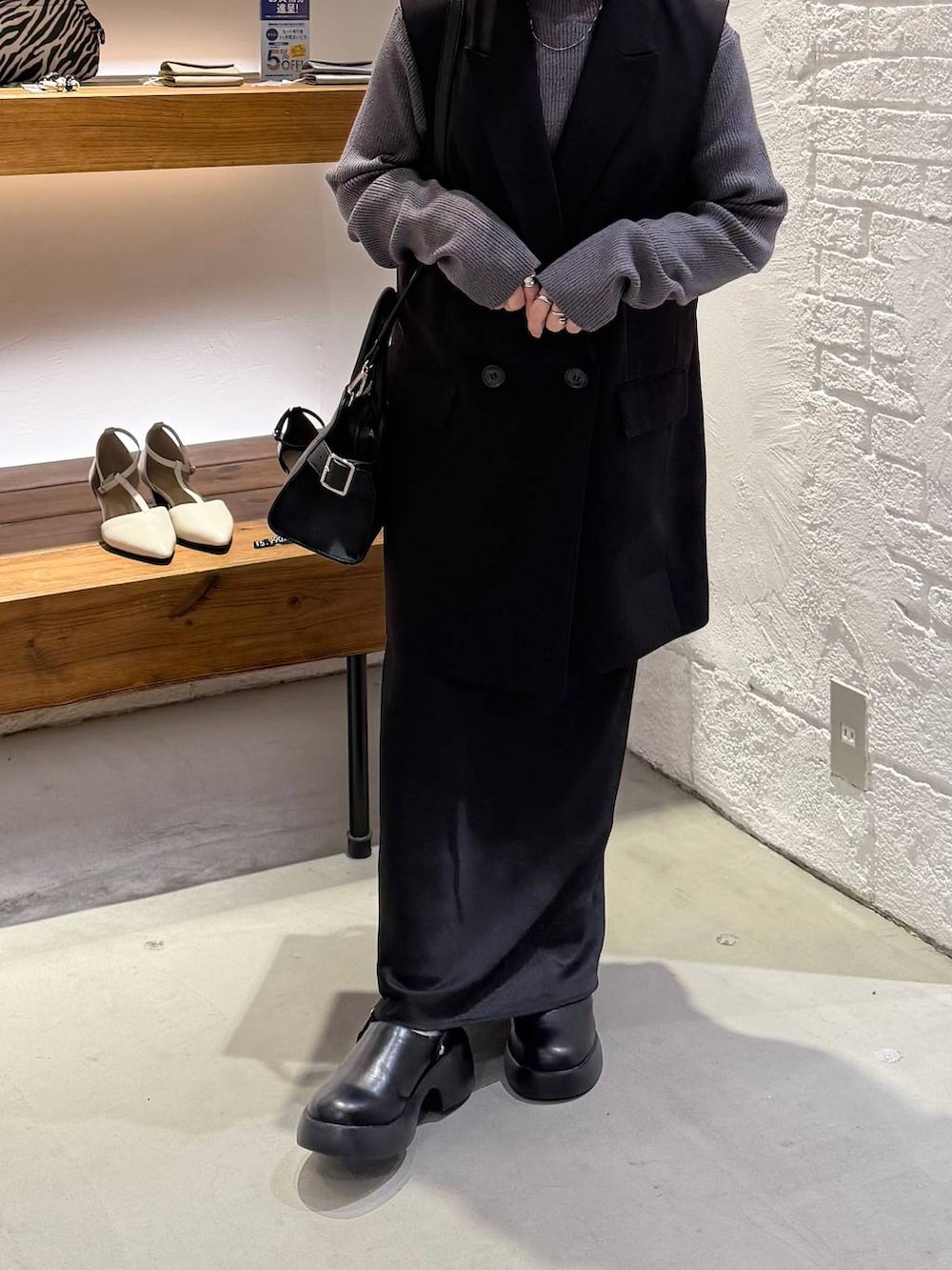 ブラック系のスカート、ブラック系のサンダル、グレー系のニット/セーターを着用したレディースの冬コーディネートの2枚目の写真
