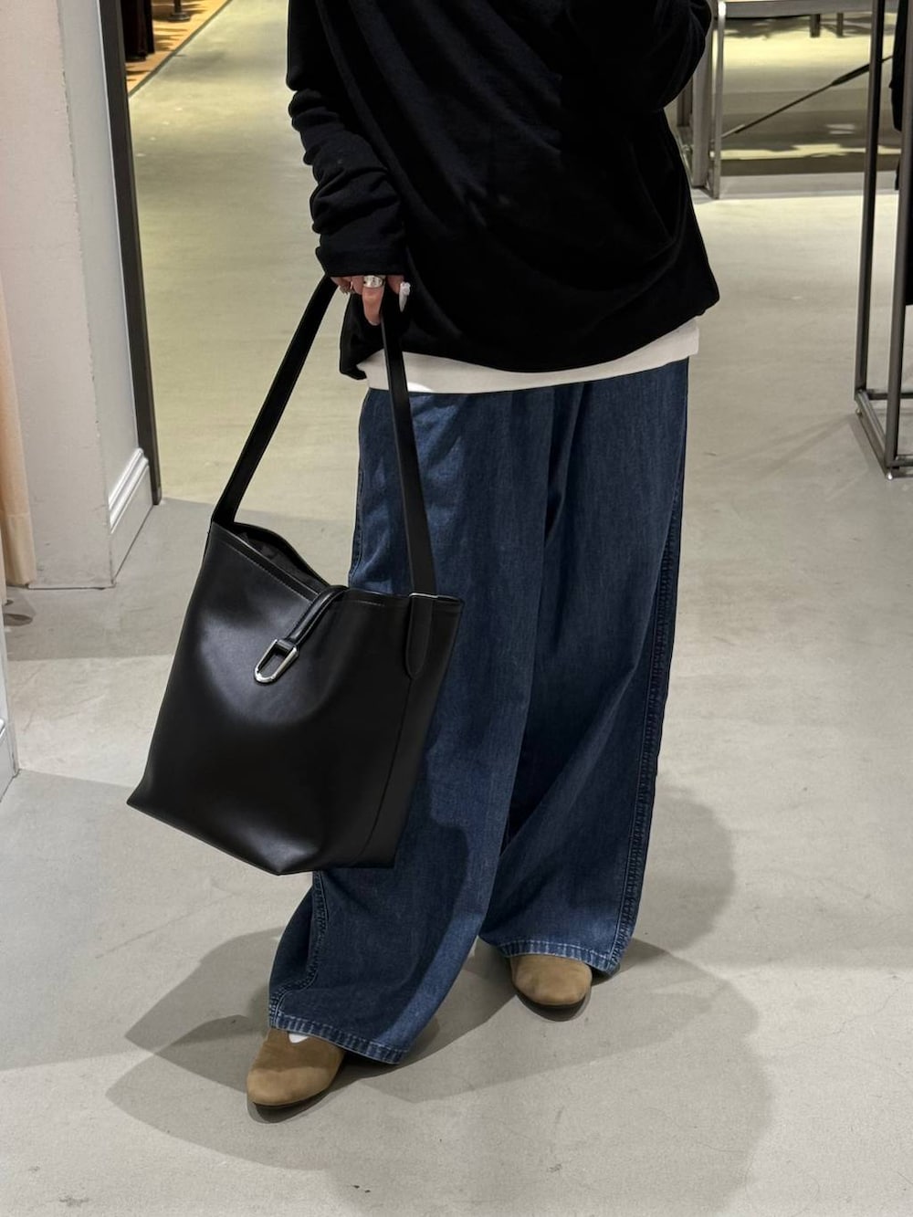 ブルー系のデニムパンツ、ブラック系のトートバッグ、ベージュ系のパンプスを着用したレディースの春コーディネートの3枚目の写真