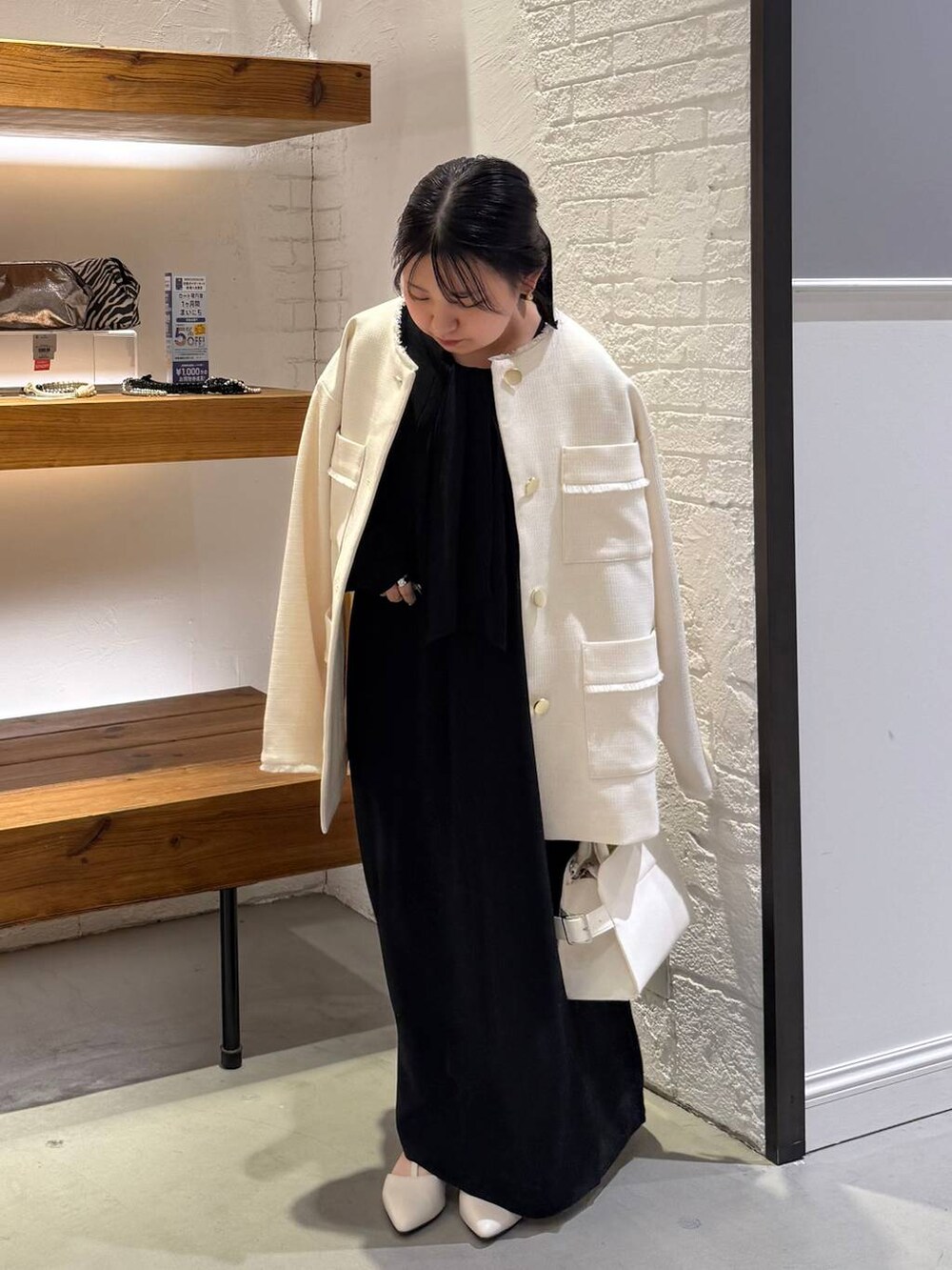 ホワイト系のノーカラージャケット、ブルー系のワンピース、ホワイト系のショルダーバッグを着用したレディースの冬コーディネートの2枚目の写真