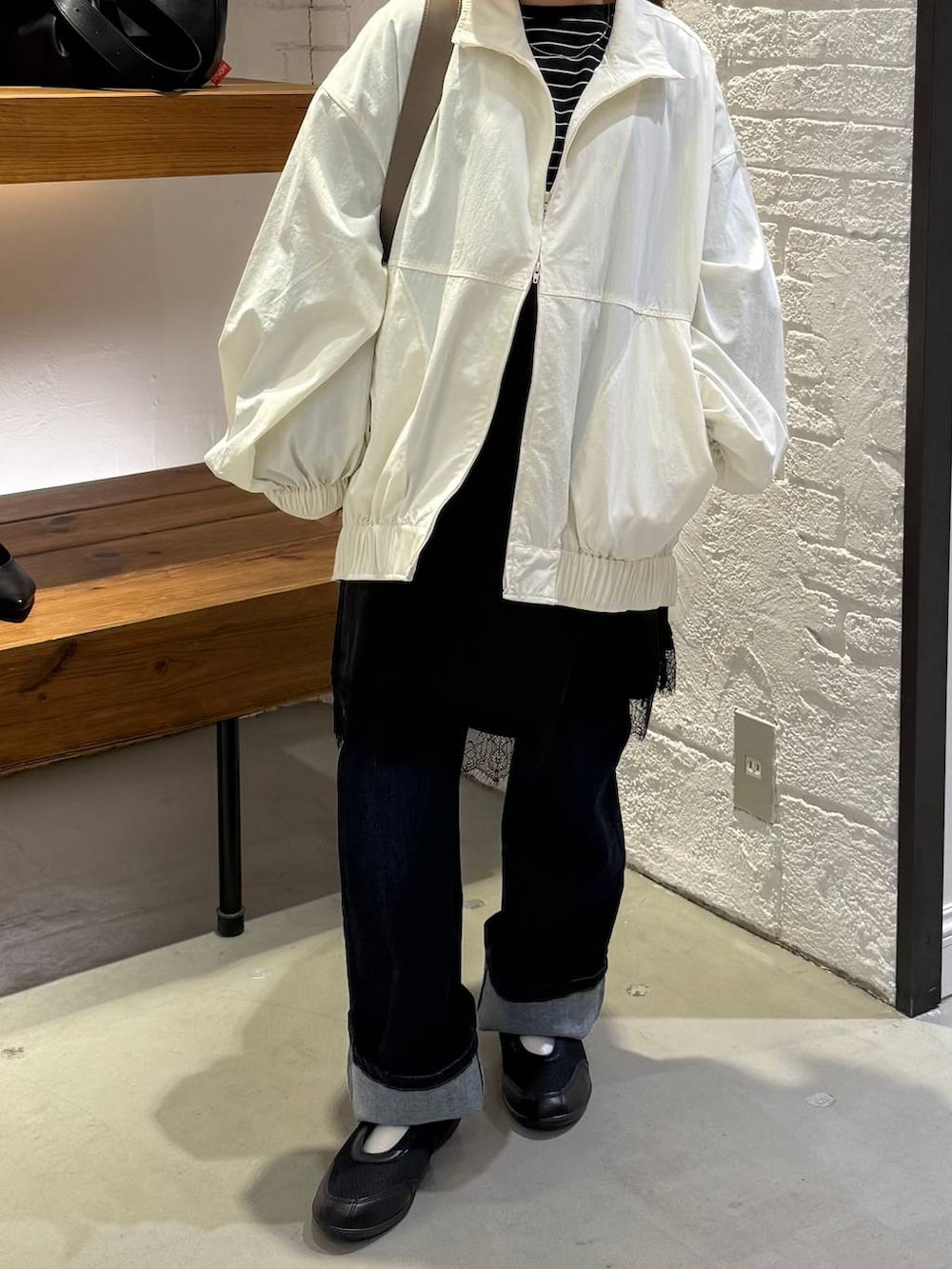 ブラック系のチュニック、ブラウン系のショルダーバッグ、ホワイト系のブルゾンを着用したレディースの冬コーディネートの2枚目の写真