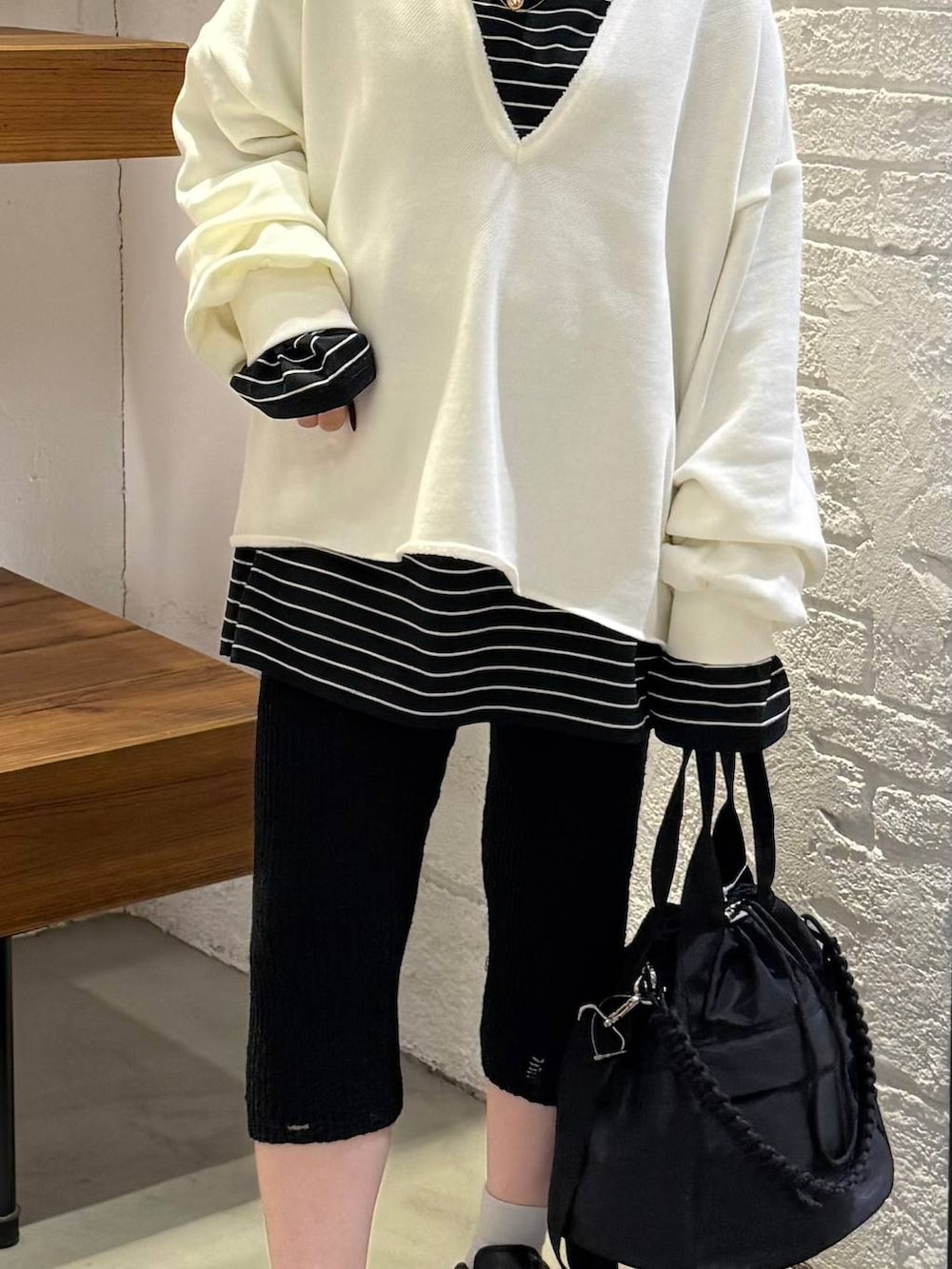 ブラック系のショルダーバッグ、ブラック系のTシャツ/カットソー、ブラック系のその他パンツを着用したレディースの冬コーディネートの2枚目の写真