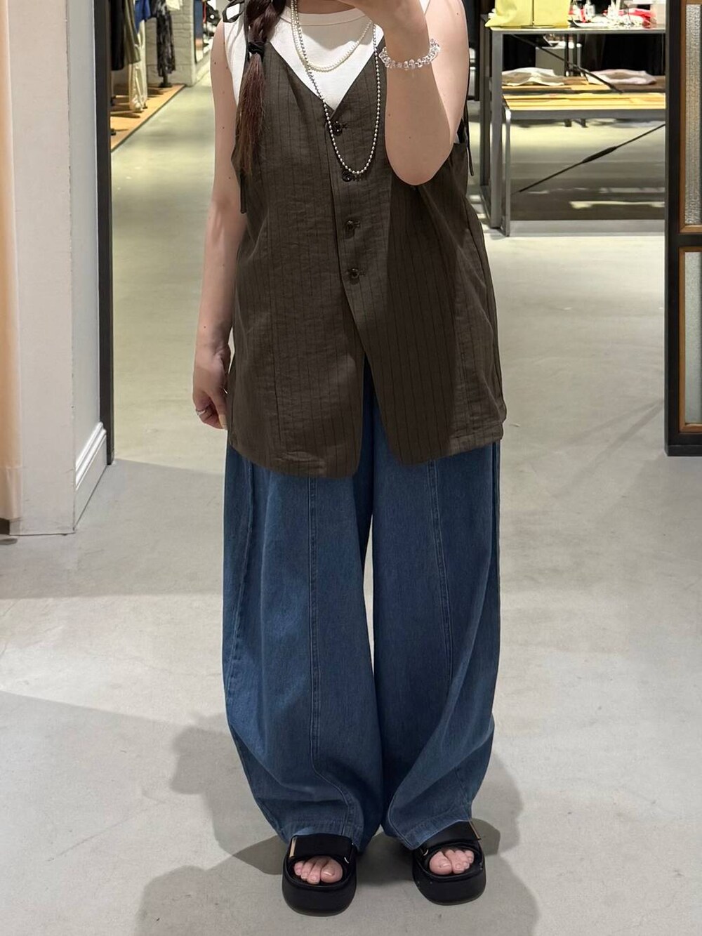 ホワイト系のタンクトップ、ブルー系のデニムパンツ、ブラック系のサンダルを着用したレディースの夏コーディネートの3枚目の写真