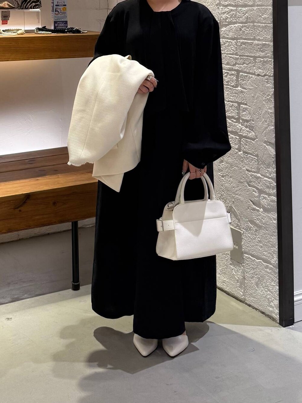 ホワイト系のノーカラージャケット、ブルー系のワンピース、ホワイト系のショルダーバッグを着用したレディースの冬コーディネートの3枚目の写真