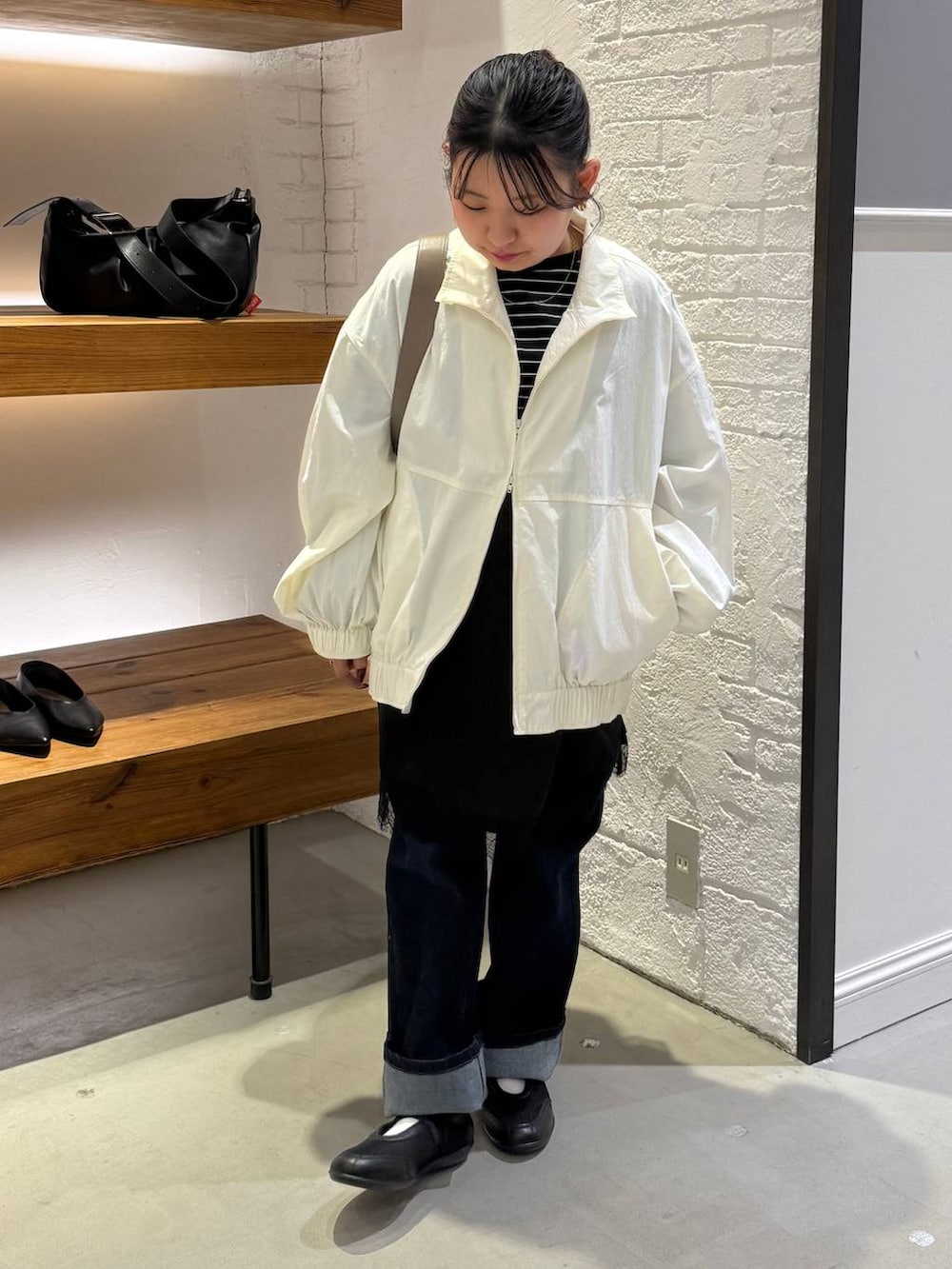 ブラック系のチュニック、ブラウン系のショルダーバッグ、ホワイト系のブルゾンを着用したレディースの冬コーディネートの3枚目の写真