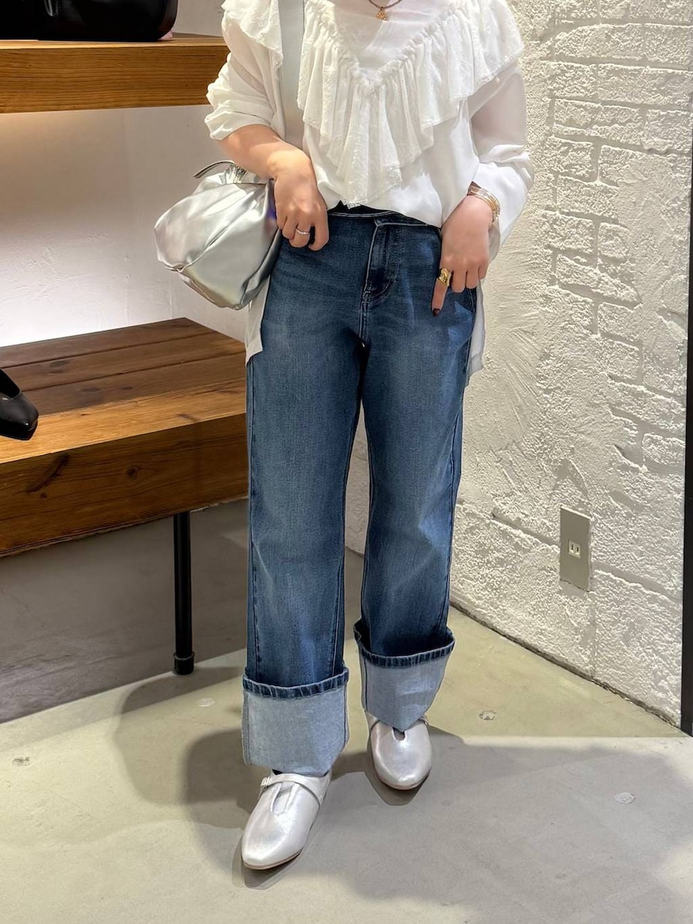 シルバー系のショルダーバッグ、ブルー系のデニムパンツ、シルバー系のパンプスを着用したレディースの冬コーディネートの2枚目の写真