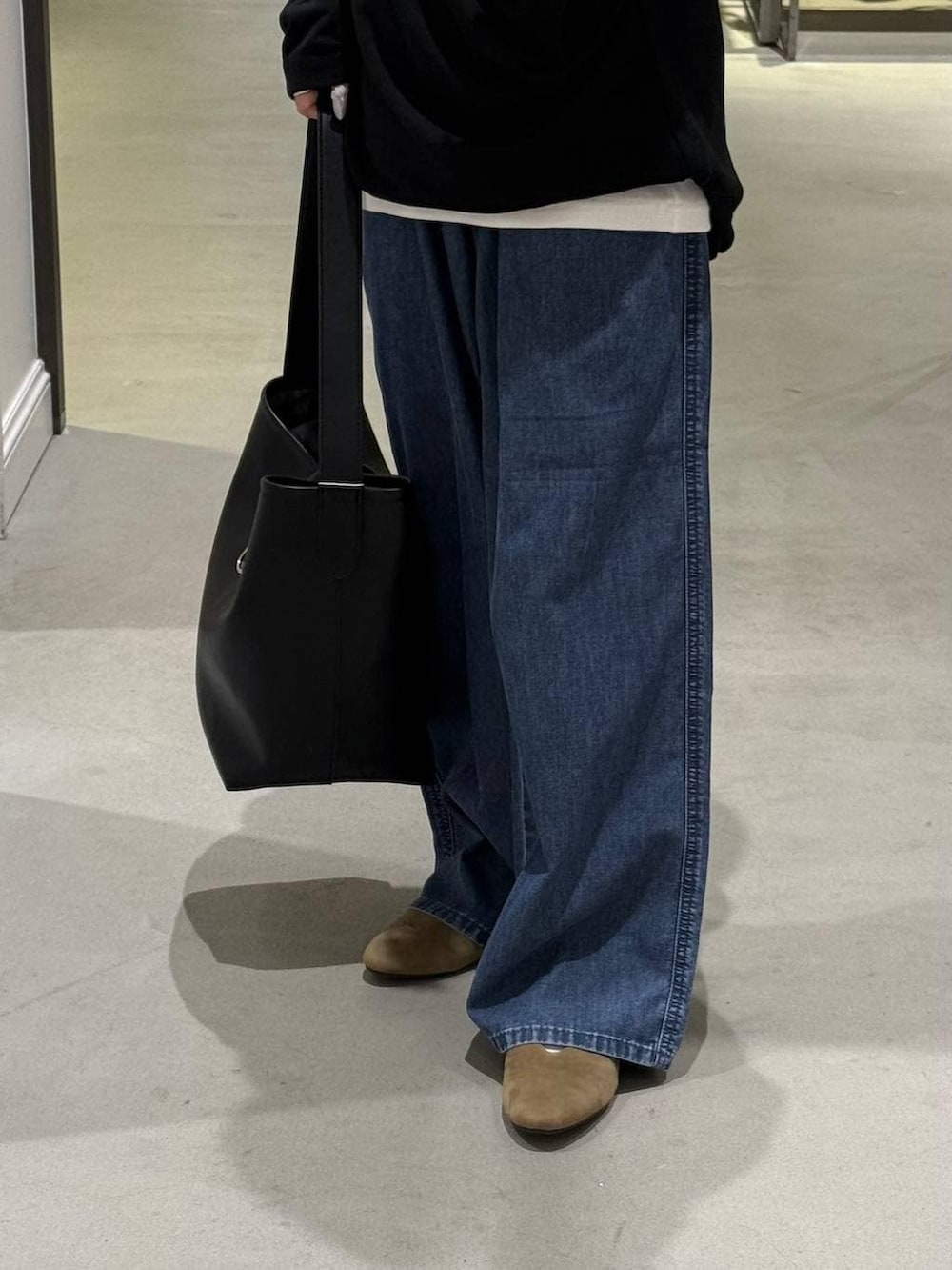 ブルー系のデニムパンツ、ブラック系のトートバッグ、ベージュ系のパンプスを着用したレディースの春コーディネートの4枚目の写真