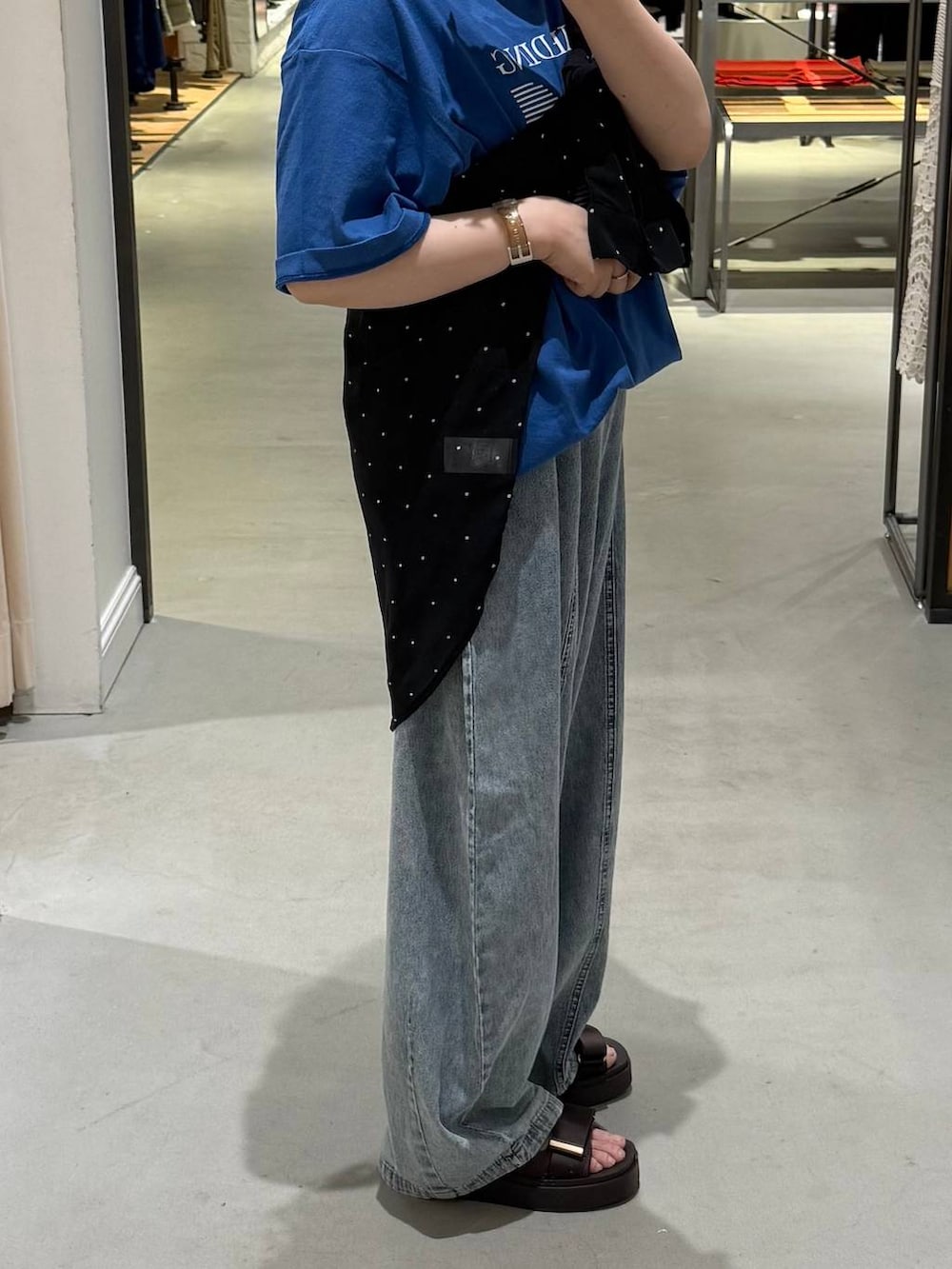 ブルー系のデニムパンツ、ブラック系のシャツ/ブラウス、ブラウン系のサンダルを着用したレディースの夏コーディネートの3枚目の写真