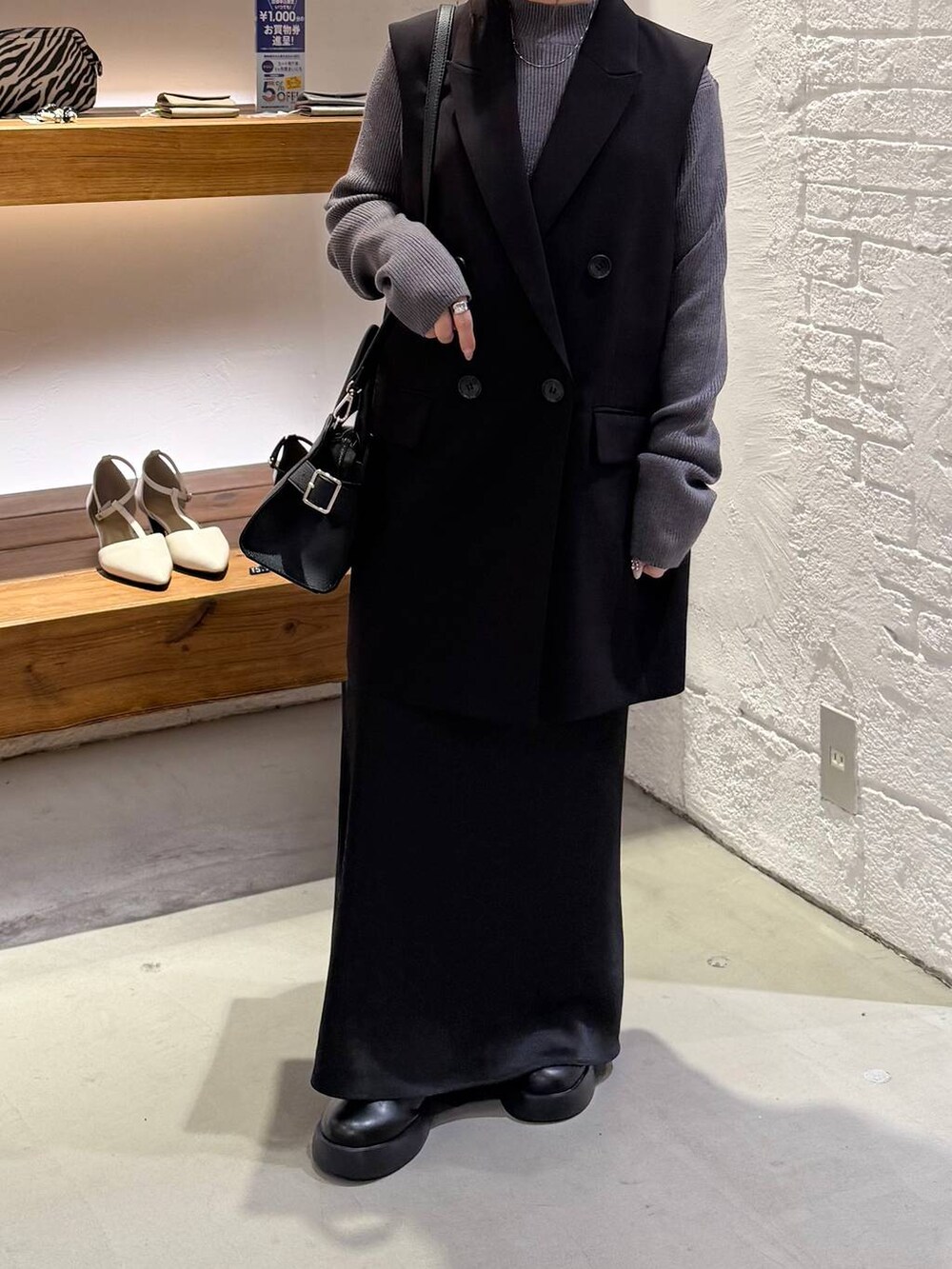 ブラック系のスカート、ブラック系のサンダル、グレー系のニット/セーターを着用したレディースの冬コーディネートの3枚目の写真