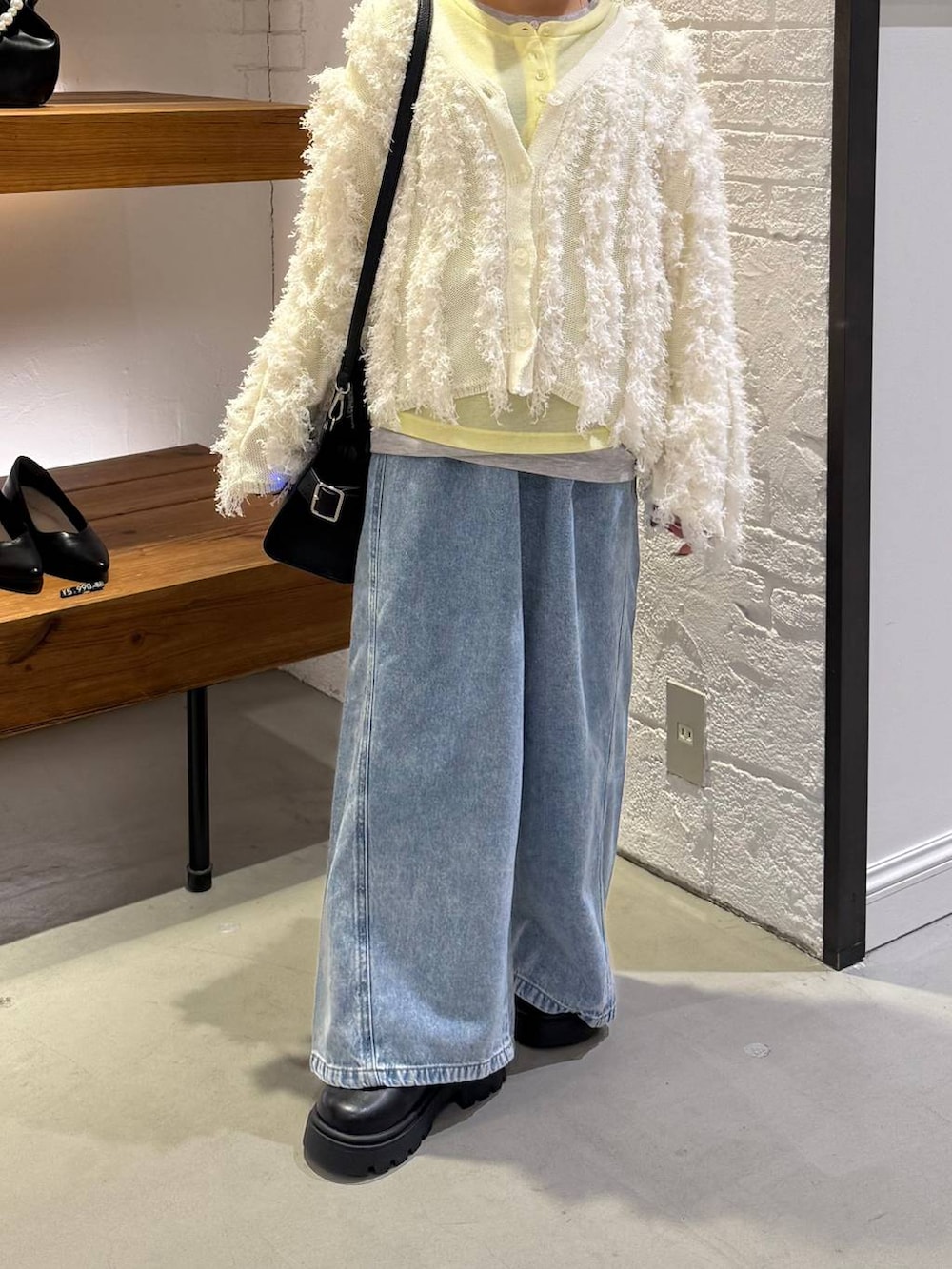 ブラック系のショルダーバッグ、イエロー系のTシャツ/カットソー、ブルー系のデニムパンツを着用したレディースの冬コーディネートの2枚目の写真