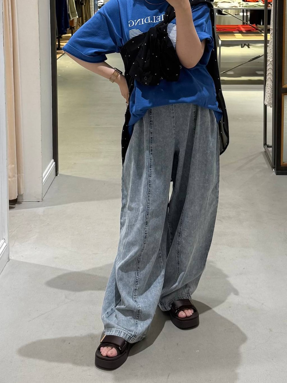 ブルー系のデニムパンツ、ブラック系のシャツ/ブラウス、ブラウン系のサンダルを着用したレディースの夏コーディネートの2枚目の写真