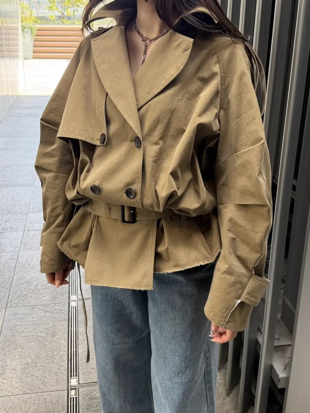 ベージュ系のトレンチコート、ブルー系のデニムパンツを着用したレディースの春コーディネートの2枚目の写真