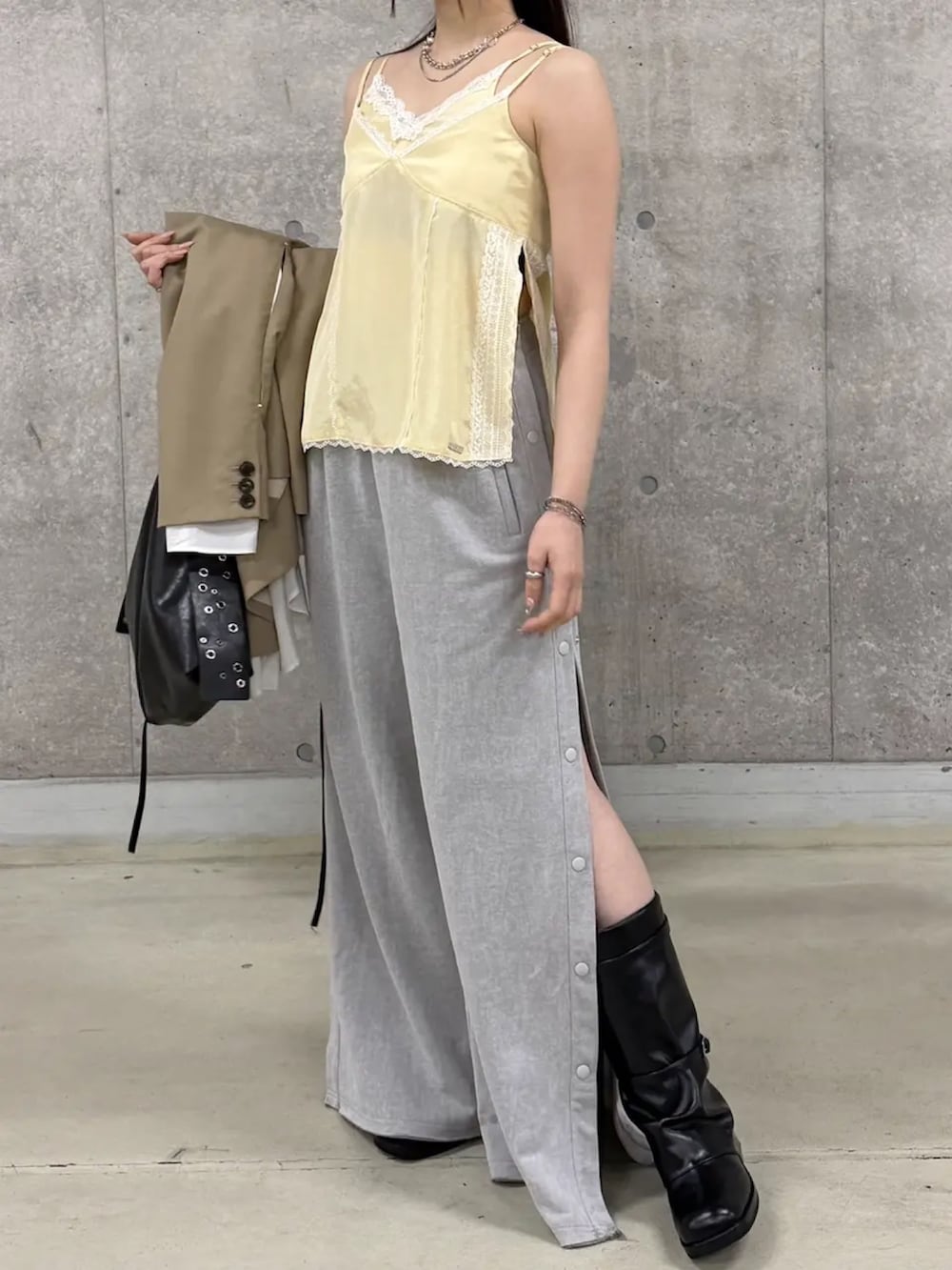 イエロー系のキャミソール、ベージュ系のテーラードジャケット、グレー系のスウェットパンツを着用したレディースの春コーディネートの4枚目の写真