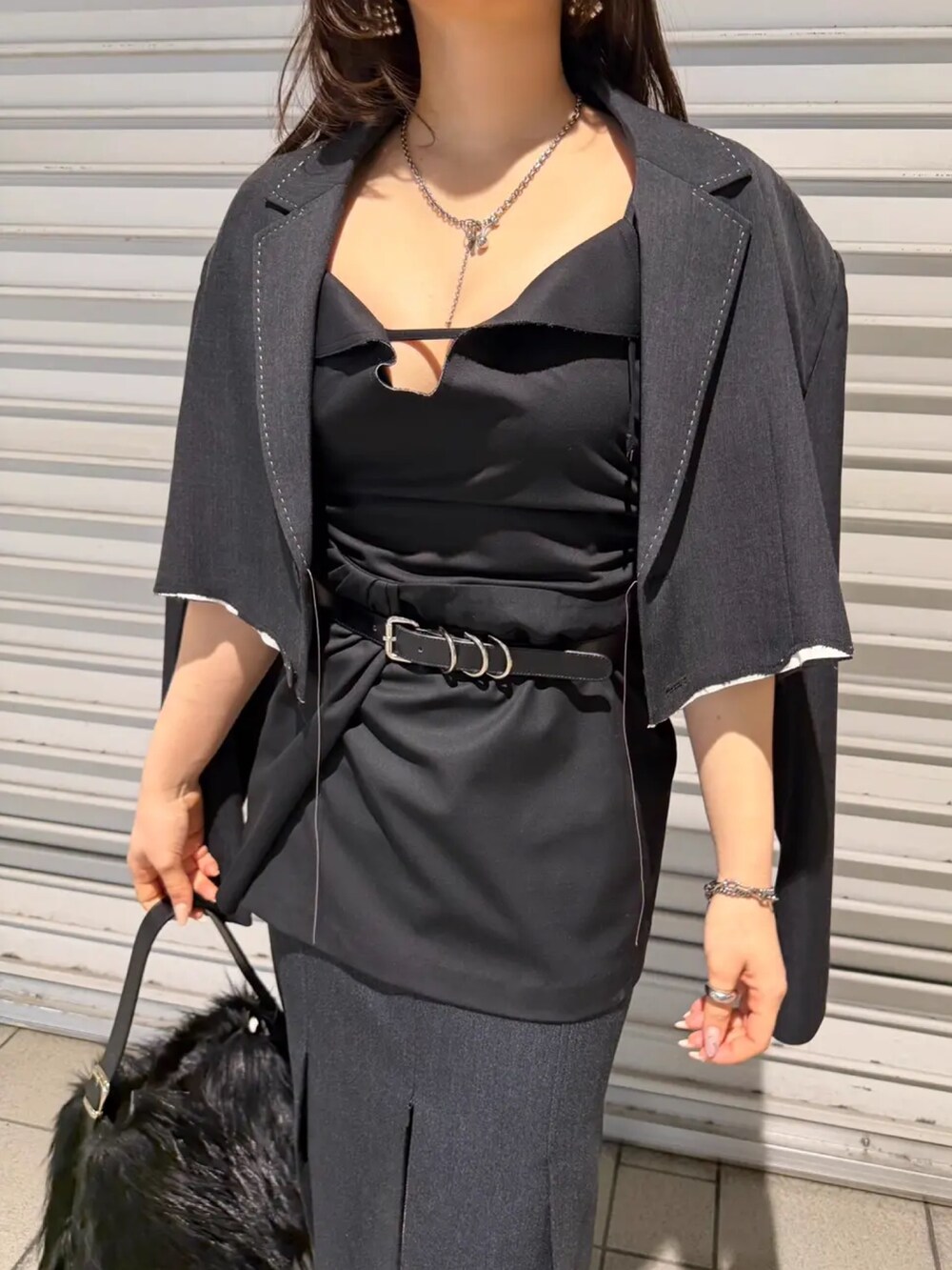 グレー系のスカート、ブラック系のドレス、ブラック系のテーラードジャケットを着用したレディースの春コーディネートの4枚目の写真