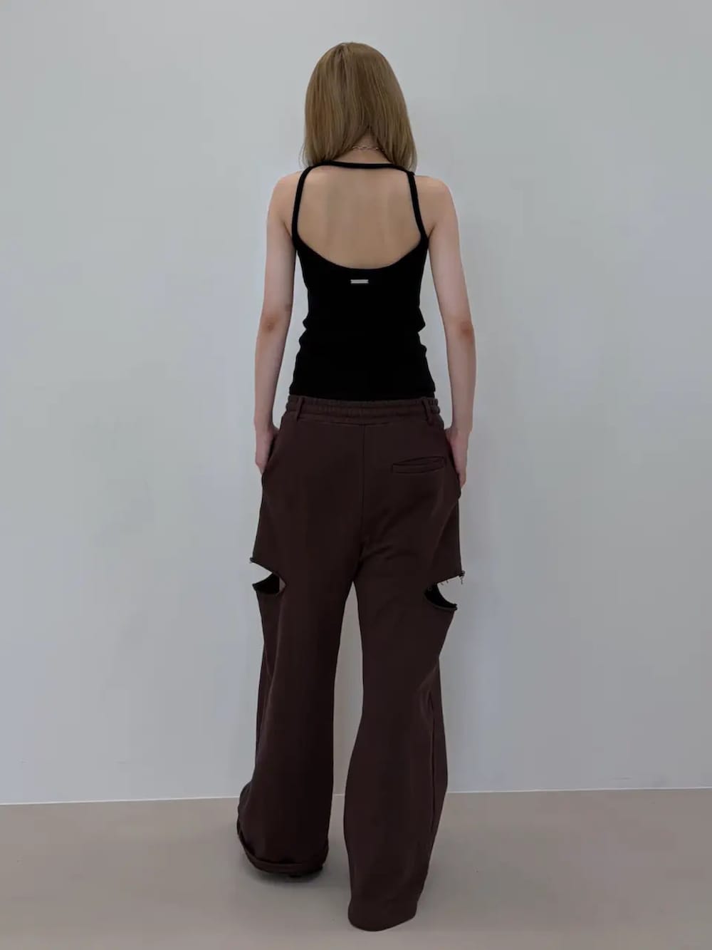 ブラック系のタンクトップ、ブラウン系のスウェットパンツ、ブラック系のサンダルを着用したレディースの夏コーディネートの3枚目の写真