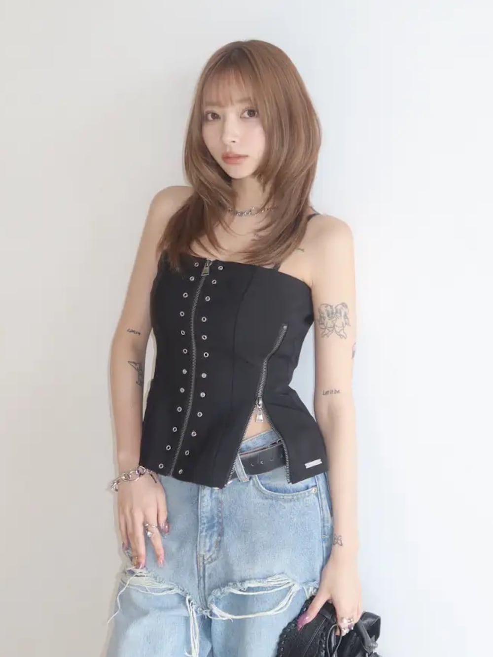 ブラック系のチューブトップ、ブルー系のデニムパンツ、ブラック系のブーツを着用したレディースの夏コーディネートの2枚目の写真