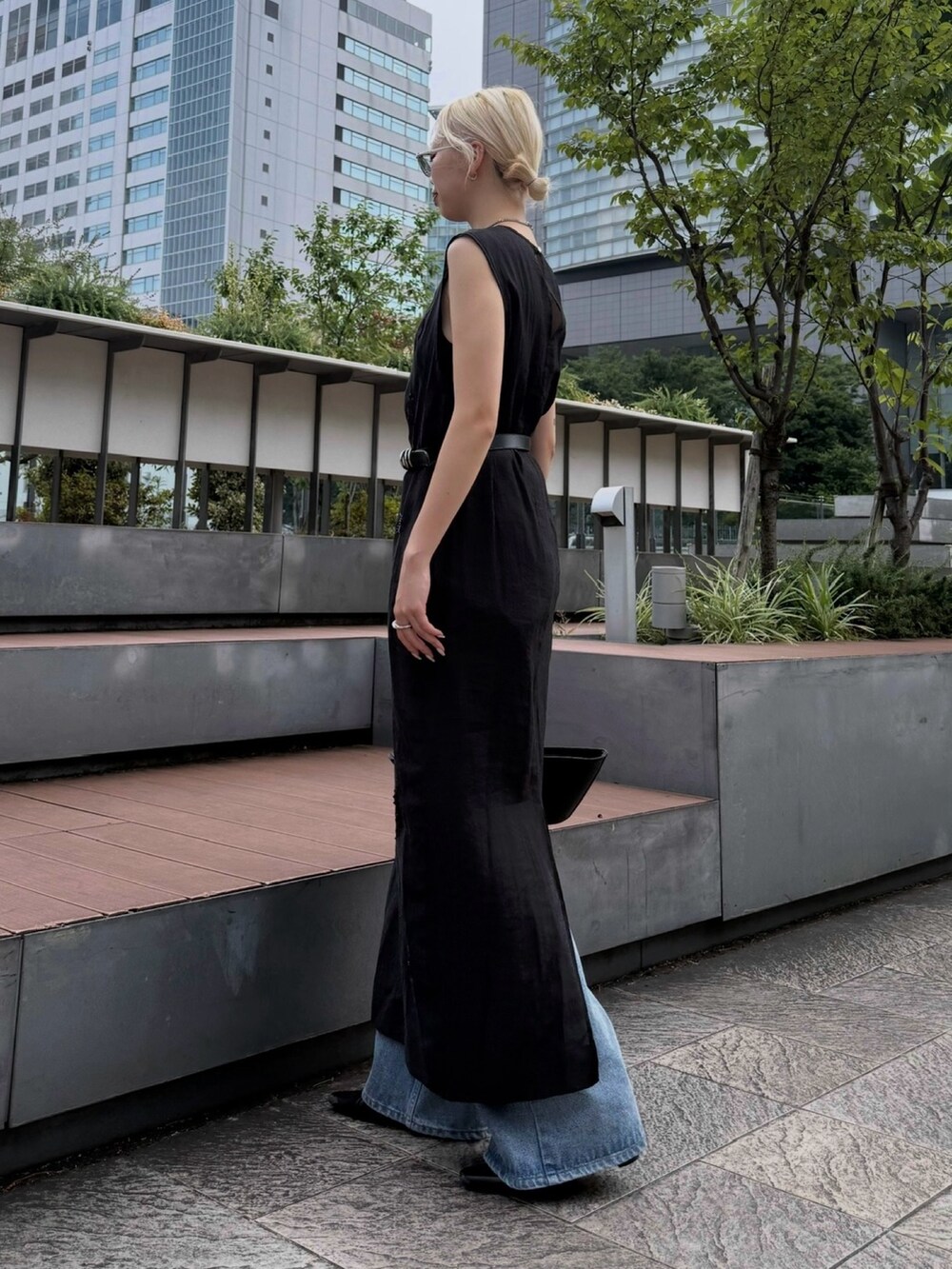 ブラック系のワンピース、ブルー系のデニムパンツ、ブラック系のハンドバッグを着用したレディースの夏コーディネートの2枚目の写真