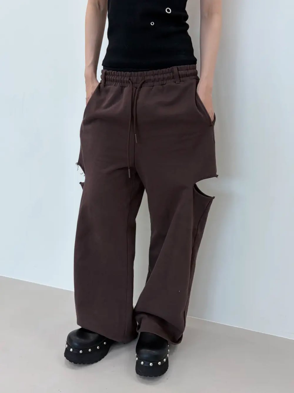 ブラック系のタンクトップ、ブラウン系のスウェットパンツ、ブラック系のサンダルを着用したレディースの夏コーディネートの5枚目の写真