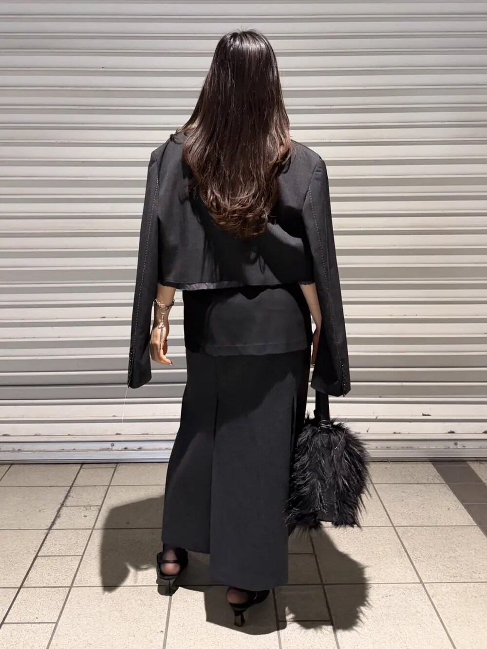 グレー系のスカート、ブラック系のドレス、ブラック系のテーラードジャケットを着用したレディースの春コーディネートの3枚目の写真