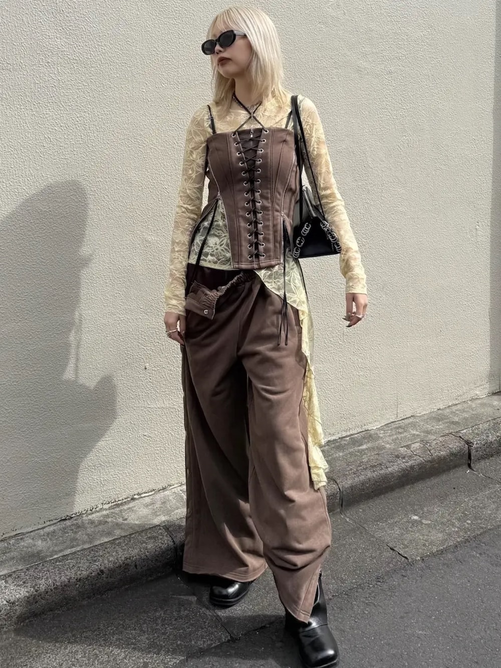 ブラウン系のスウェットパンツ、ブラック系のブーツ、ブラウン系のその他トップスを着用したレディースの春コーディネートの3枚目の写真