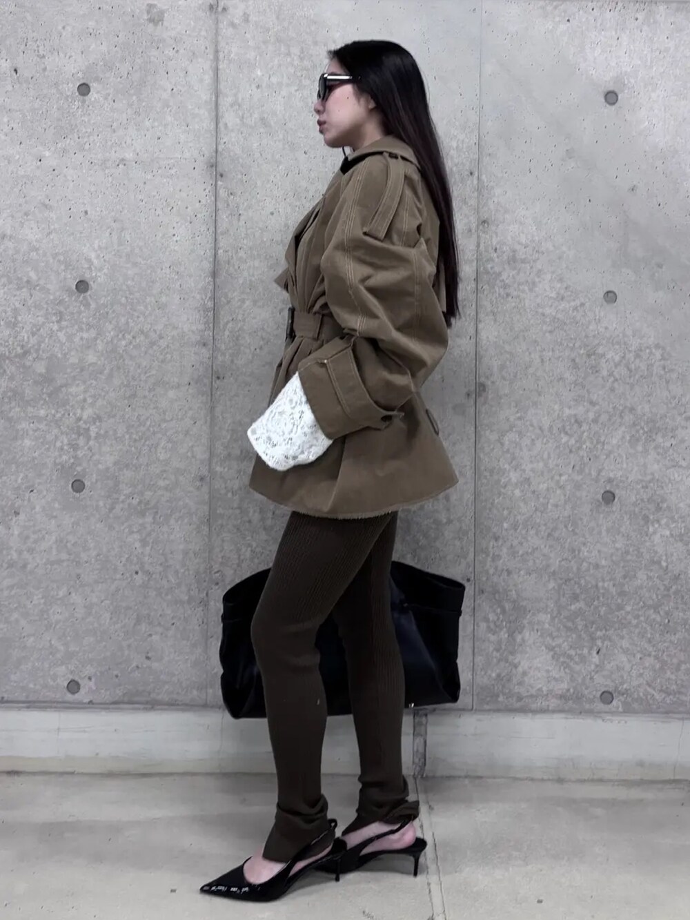 ベージュ系のトレンチコート、ホワイト系のシャツ/ブラウス、ブラック系のボストンバッグを着用したレディースの冬コーディネートの2枚目の写真