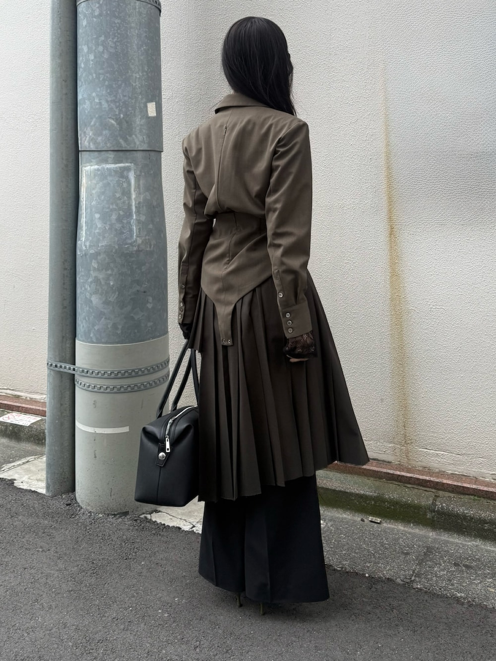 ブラック系のボストンバッグ、グリーン系のブーツ、ブラック系のスカートを着用したレディースの冬コーディネートの2枚目の写真