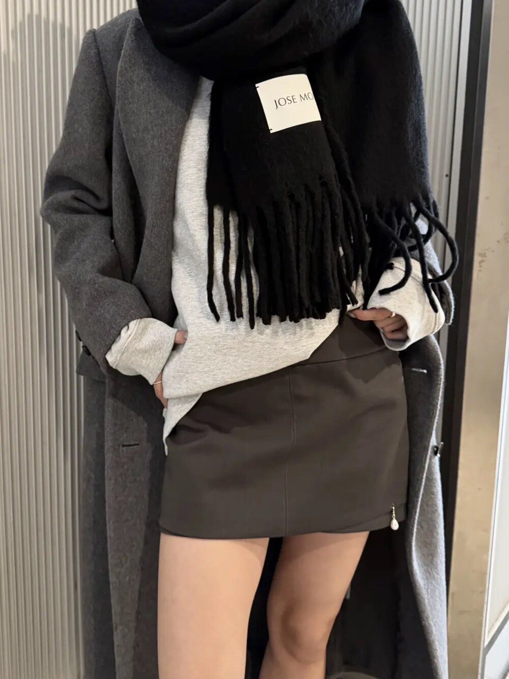 ブラック系のパンプス、グレー系のスカート、グレー系のスウェットを着用したレディースの冬コーディネートの4枚目の写真