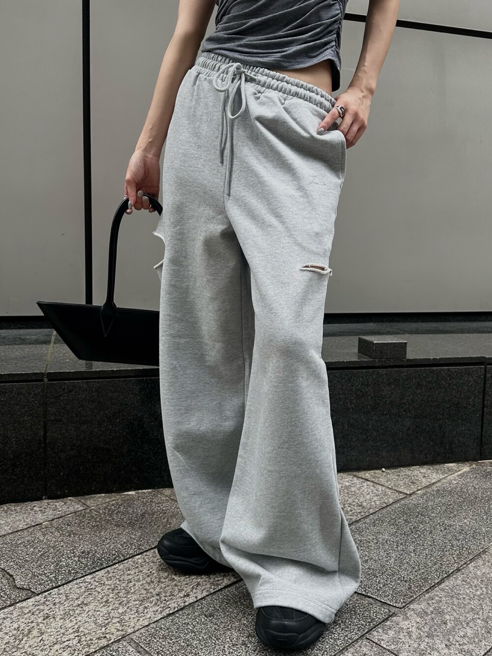 グレー系のTシャツ/カットソー、ブラック系のハンドバッグ、グレー系のスウェットパンツを着用したレディースの夏コーディネートの3枚目の写真