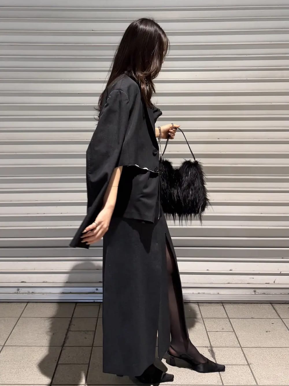 グレー系のスカート、ブラック系のドレス、ブラック系のテーラードジャケットを着用したレディースの春コーディネートの2枚目の写真