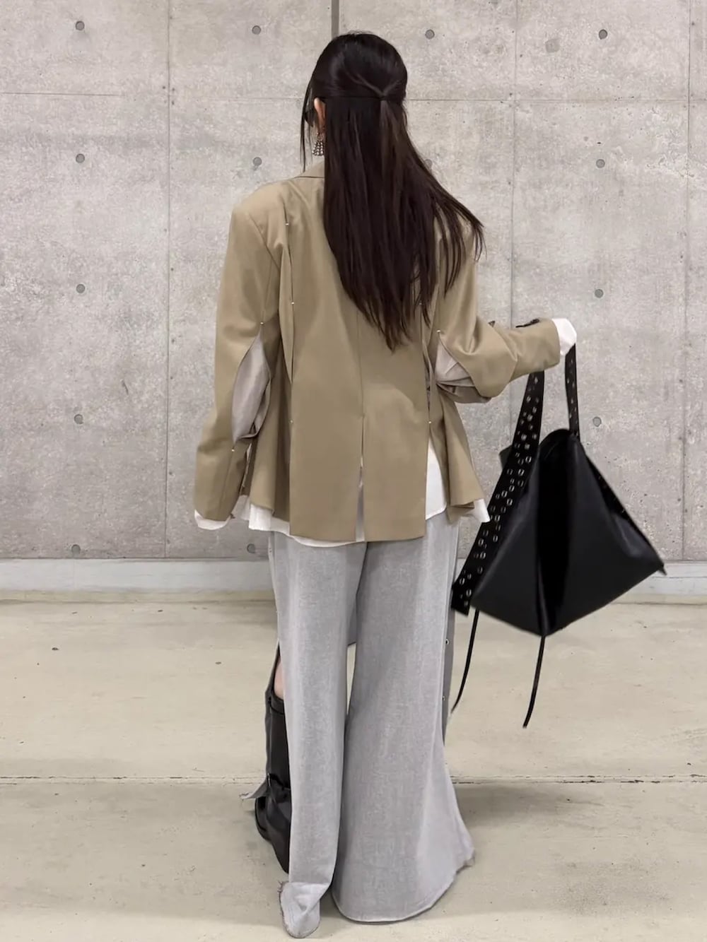 イエロー系のキャミソール、ベージュ系のテーラードジャケット、グレー系のスウェットパンツを着用したレディースの春コーディネートの3枚目の写真