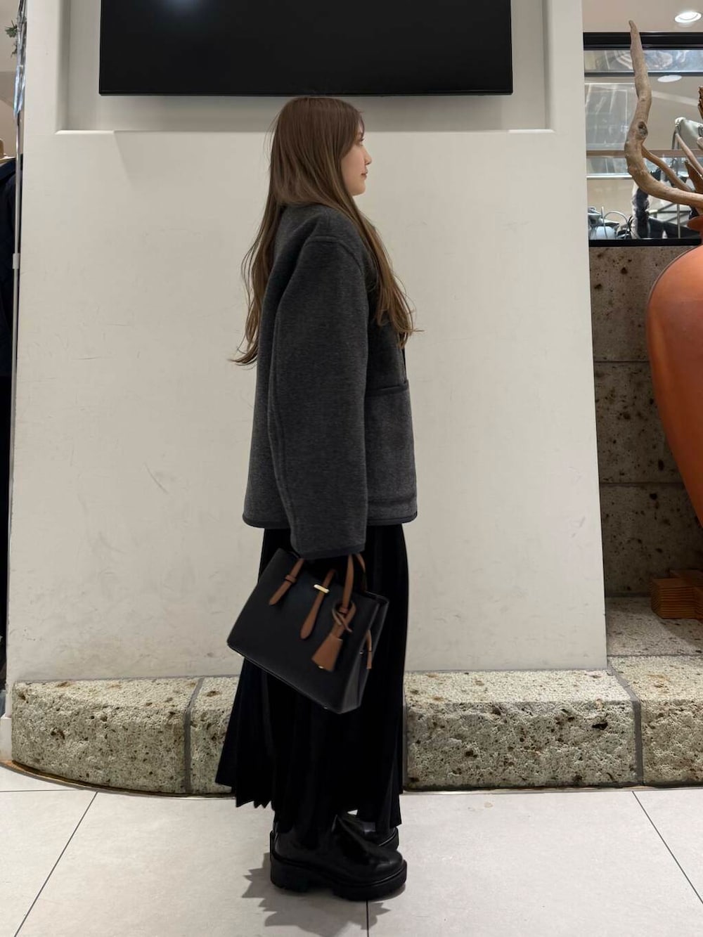 ブラック系のハンドバッグ、ブラウン系のブーツ、レッド系のニット/セーターを着用したレディースの冬コーディネートの3枚目の写真