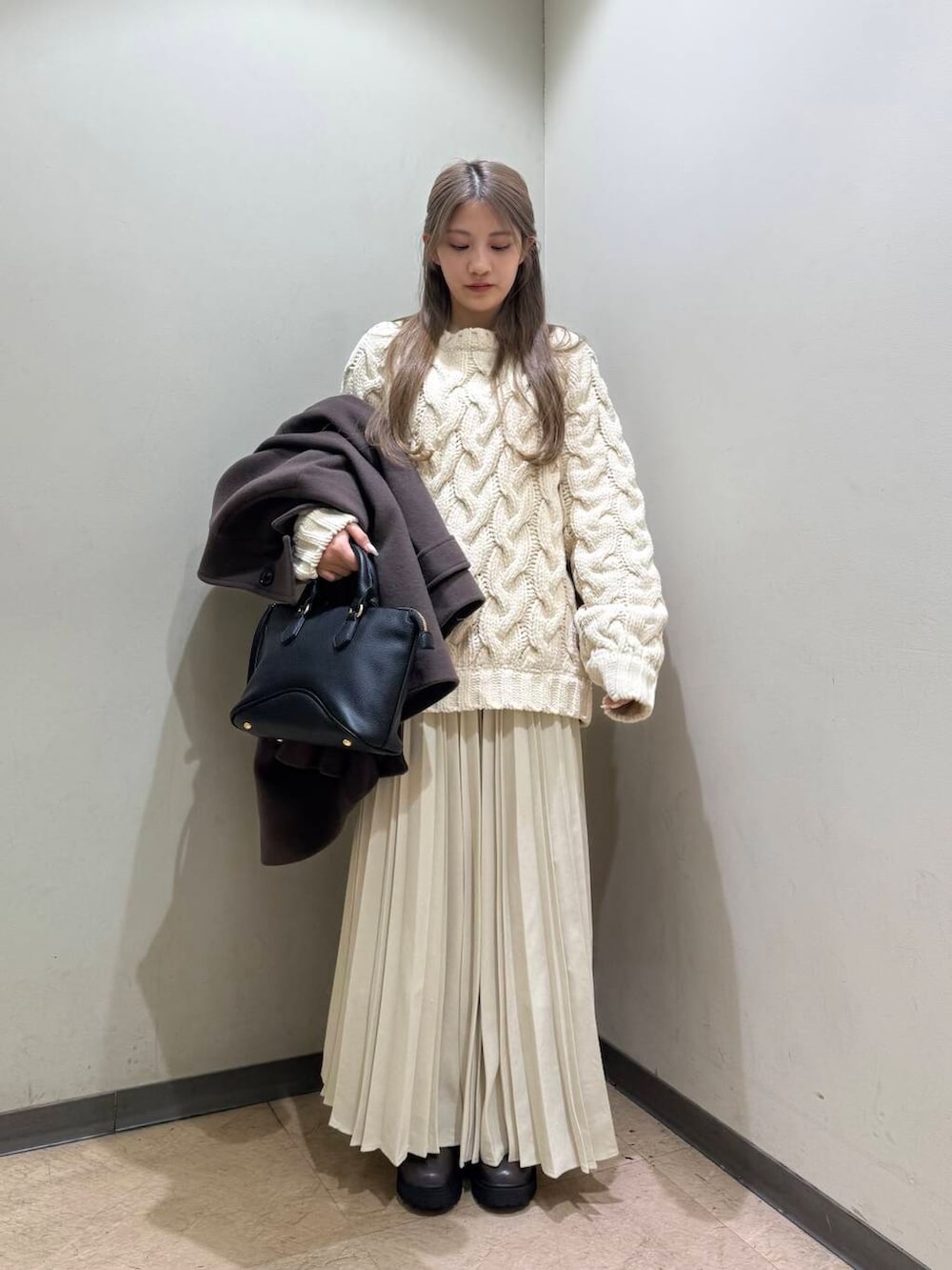 ブラック系のボストンバッグ、ブラウン系のブーツ、ブラウン系のその他アウターを着用したレディースの冬コーディネートの2枚目の写真