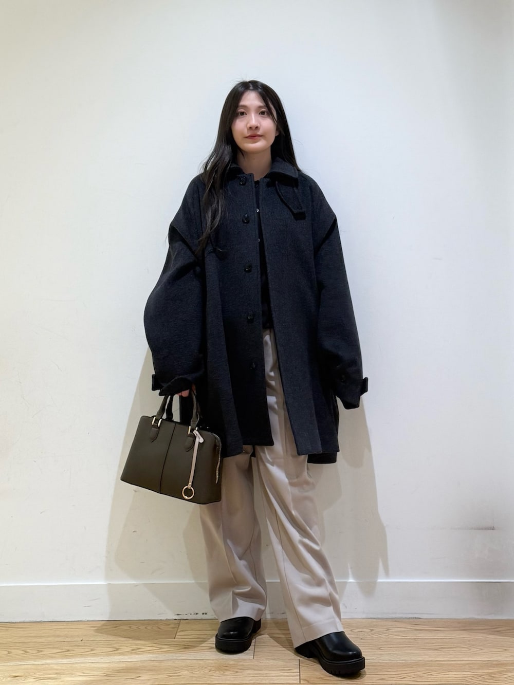 グレー系のステンカラーコート、パープル系のハンドバッグ、ベージュ系のその他パンツを着用したレディースの秋コーディネートの3枚目の写真