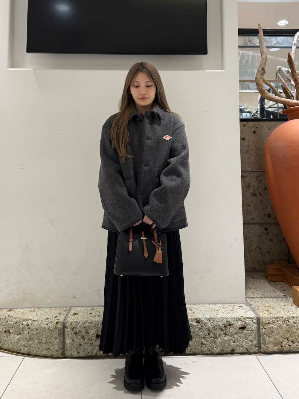 ブラック系のハンドバッグ、ブラウン系のブーツ、レッド系のニット/セーターを着用したレディースの冬コーディネートの2枚目の写真