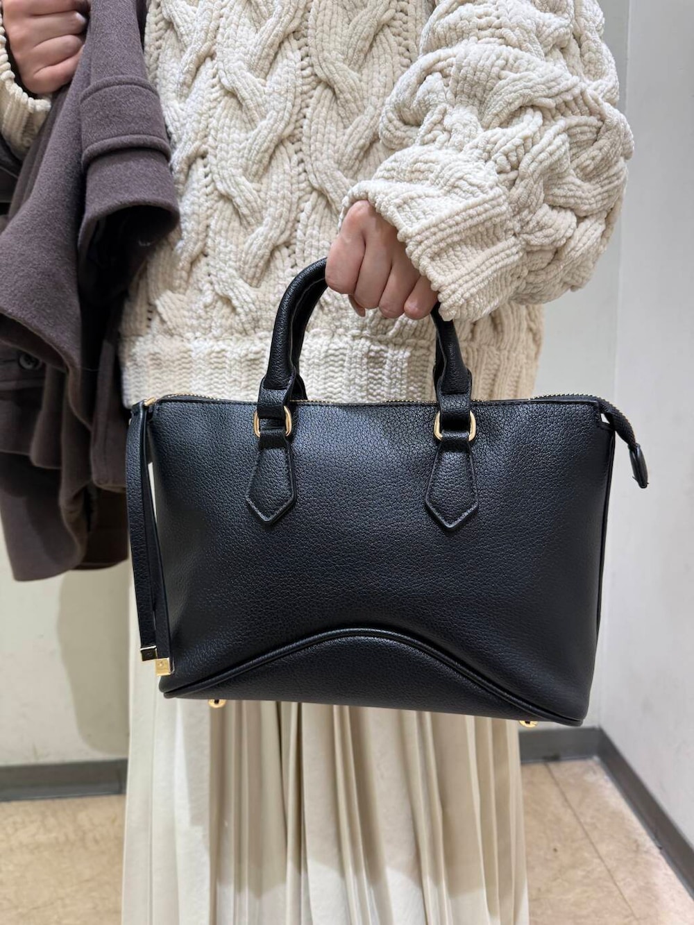 ブラック系のボストンバッグ、ブラウン系のブーツ、ブラウン系のその他アウターを着用したレディースの冬コーディネートの4枚目の写真