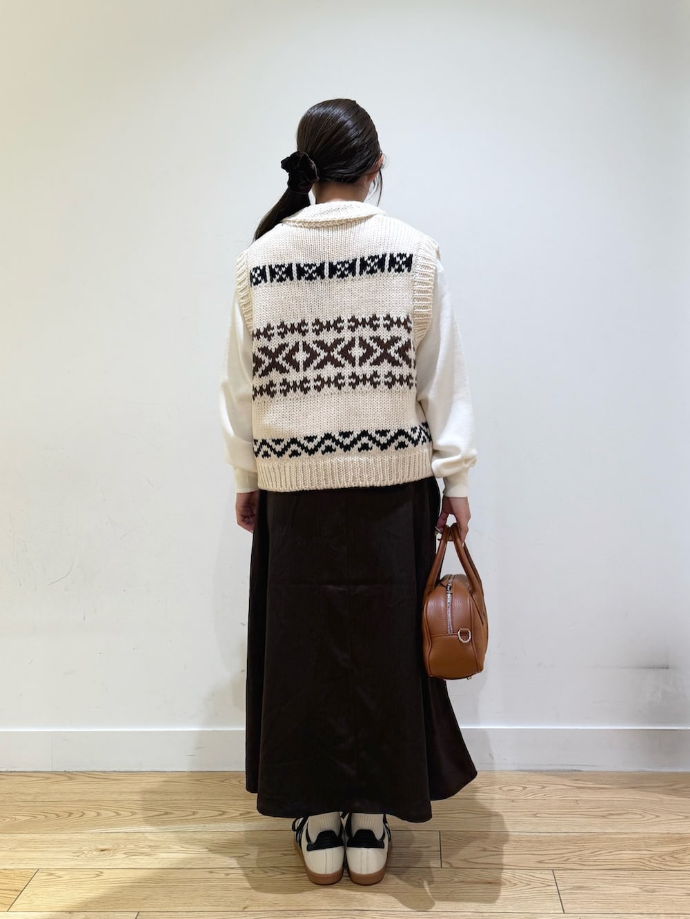 ホワイト系のベスト、ホワイト系のニット/セーター、ブラウン系のスカートを着用したレディースの秋コーディネートの6枚目の写真