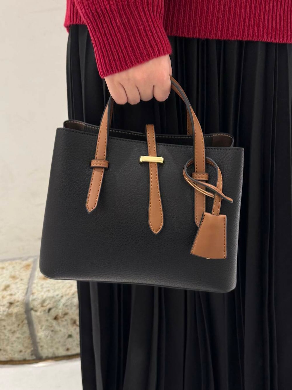 ブラック系のハンドバッグ、ブラウン系のブーツ、レッド系のニット/セーターを着用したレディースの冬コーディネートの7枚目の写真