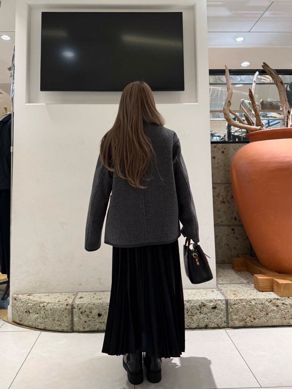 ブラック系のハンドバッグ、ブラウン系のブーツ、レッド系のニット/セーターを着用したレディースの冬コーディネートの4枚目の写真