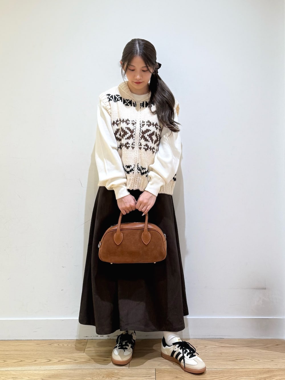 ホワイト系のベスト、ホワイト系のニット/セーター、ブラウン系のスカートを着用したレディースの秋コーディネートの4枚目の写真
