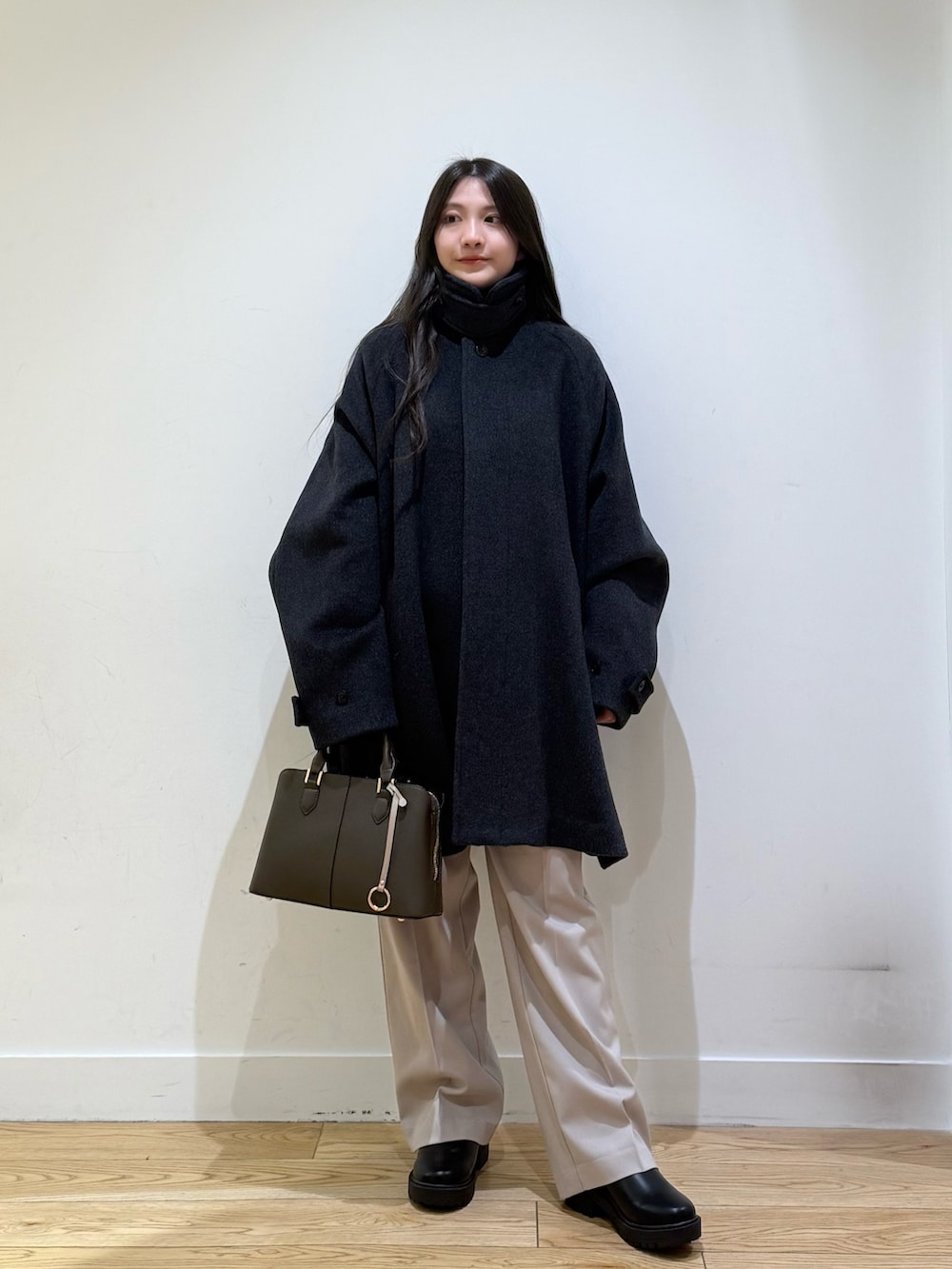 グレー系のステンカラーコート、パープル系のハンドバッグ、ベージュ系のその他パンツを着用したレディースの秋コーディネートの2枚目の写真