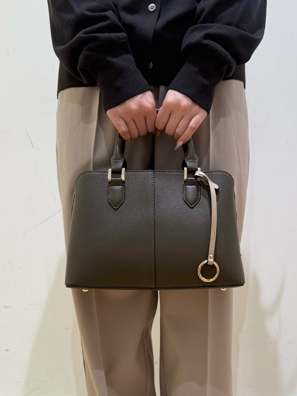 グレー系のステンカラーコート、パープル系のハンドバッグ、ベージュ系のその他パンツを着用したレディースの秋コーディネートの9枚目の写真