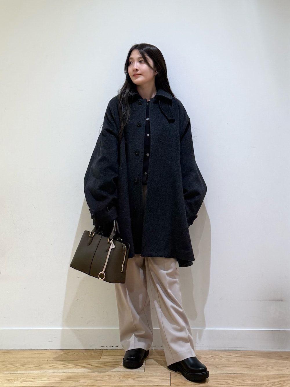 グレー系のステンカラーコート、パープル系のハンドバッグ、ベージュ系のその他パンツを着用したレディースの秋コーディネートの4枚目の写真