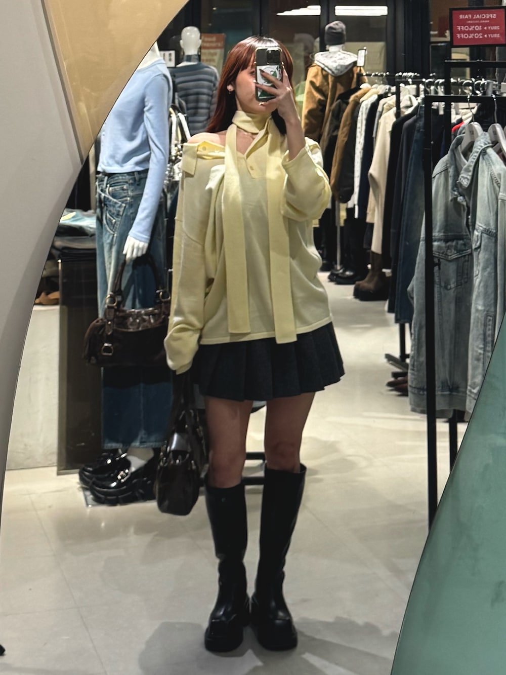 イエロー系のニット/セーター、グレー系のスカート、ブラック系のブーツを着用したレディースの冬コーディネートの2枚目の写真