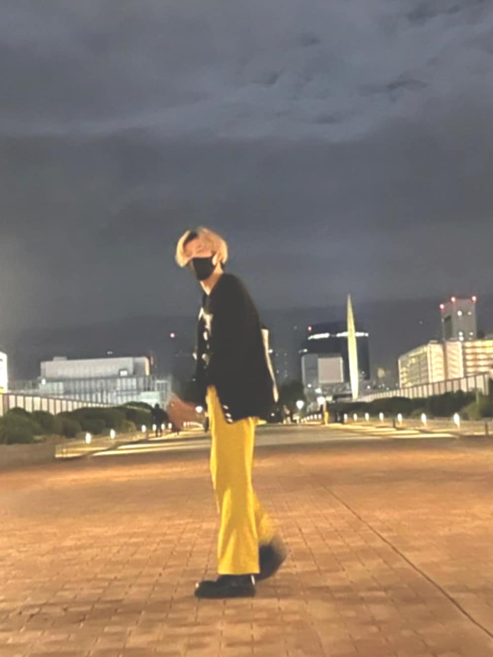 イエロー系のスラックス、ブラック系のモカシン/デッキシューズ、ブラック系のニット/セーターを着用したメンズの秋コーディネートの2枚目の写真