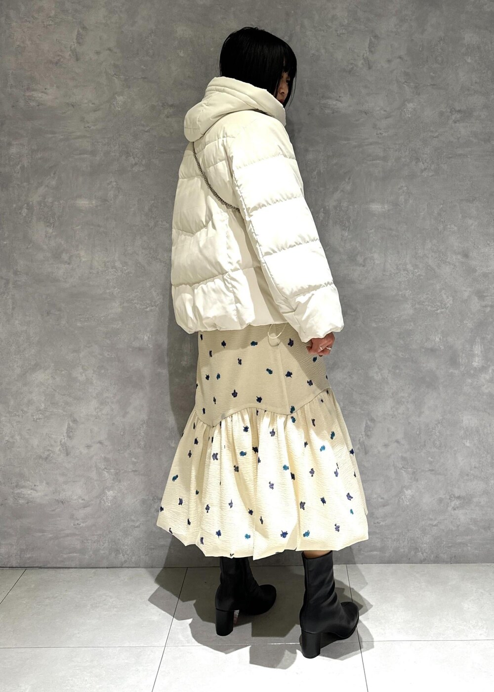 ブラック系のブーツ、ホワイト系のダウンジャケット/コート、ホワイト系のスカートを着用したレディースの冬コーディネートの4枚目の写真
