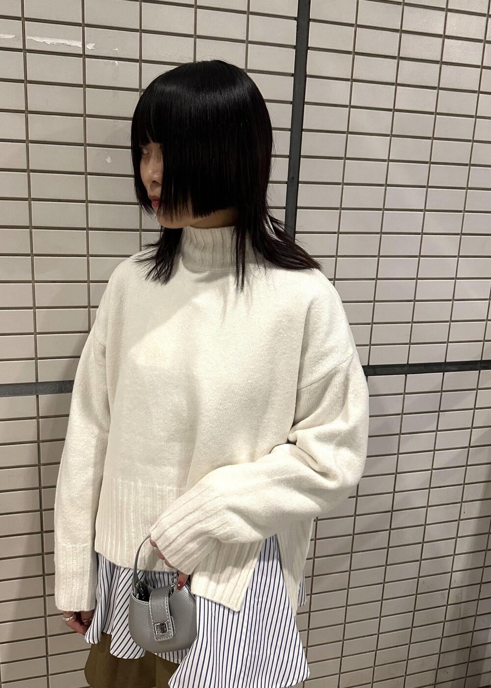 ホワイト系のニット/セーター、ブルー系のシャツ/ブラウス、イエロー系のスラックスを着用したレディースの冬コーディネートの6枚目の写真