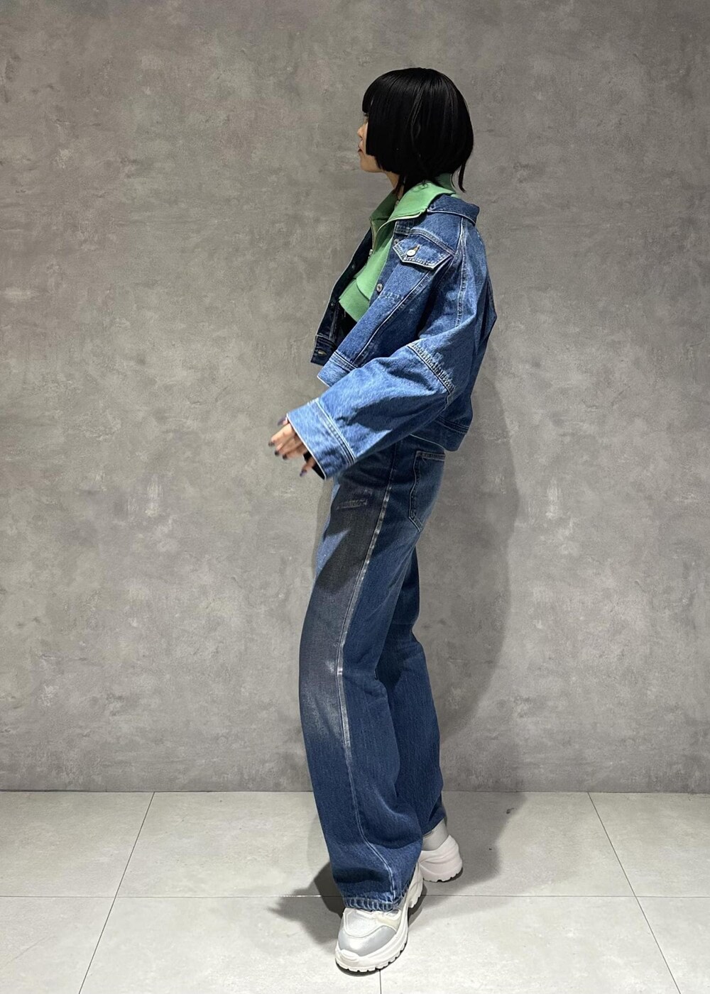 イエロー系のショルダーバッグ、シルバー系のスニーカー、グリーン系のワンピースを着用したレディースの春コーディネートの3枚目の写真