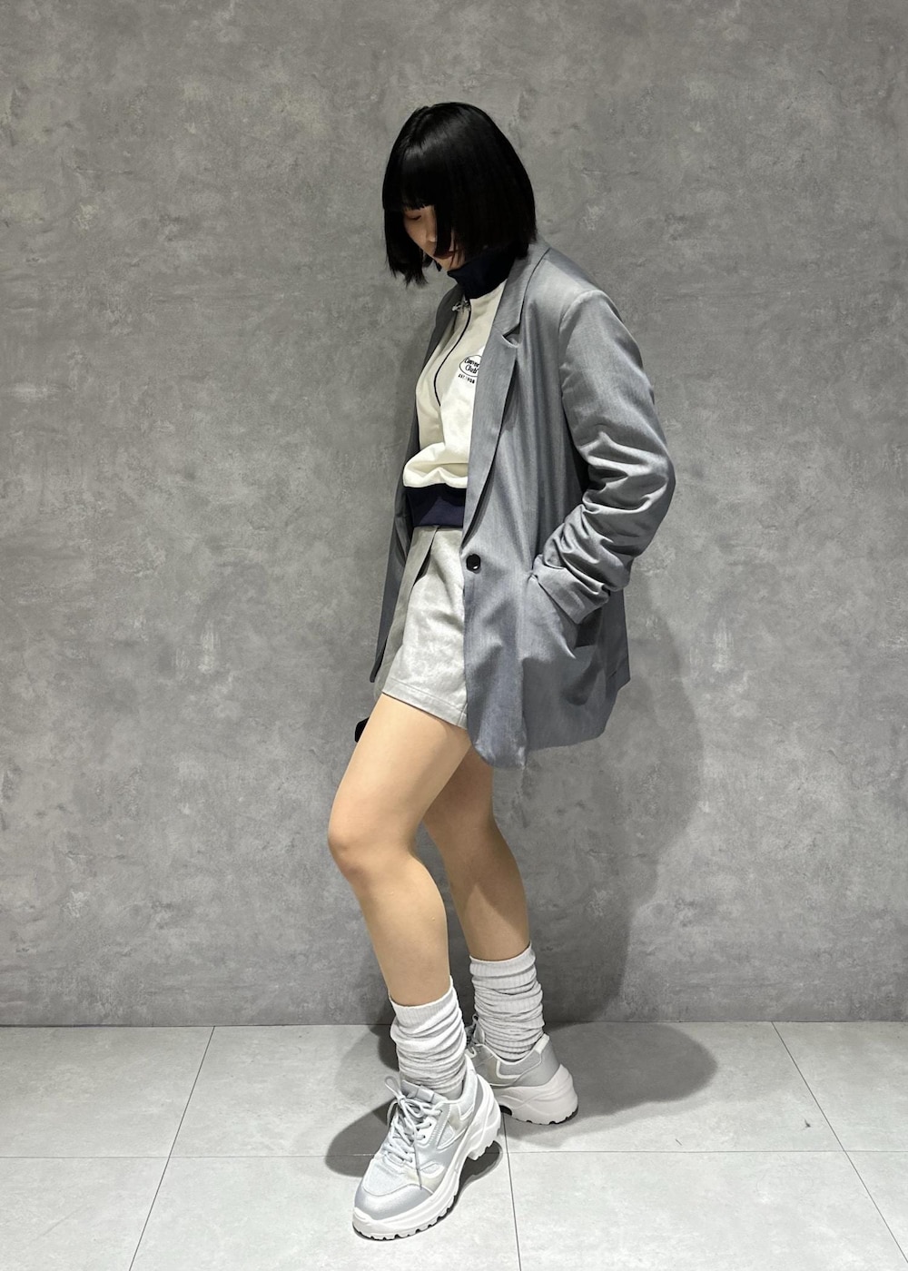 シルバー系のスニーカー、ホワイト系のブルゾン、グレー系のスラックスを着用したレディースの春コーディネートの5枚目の写真