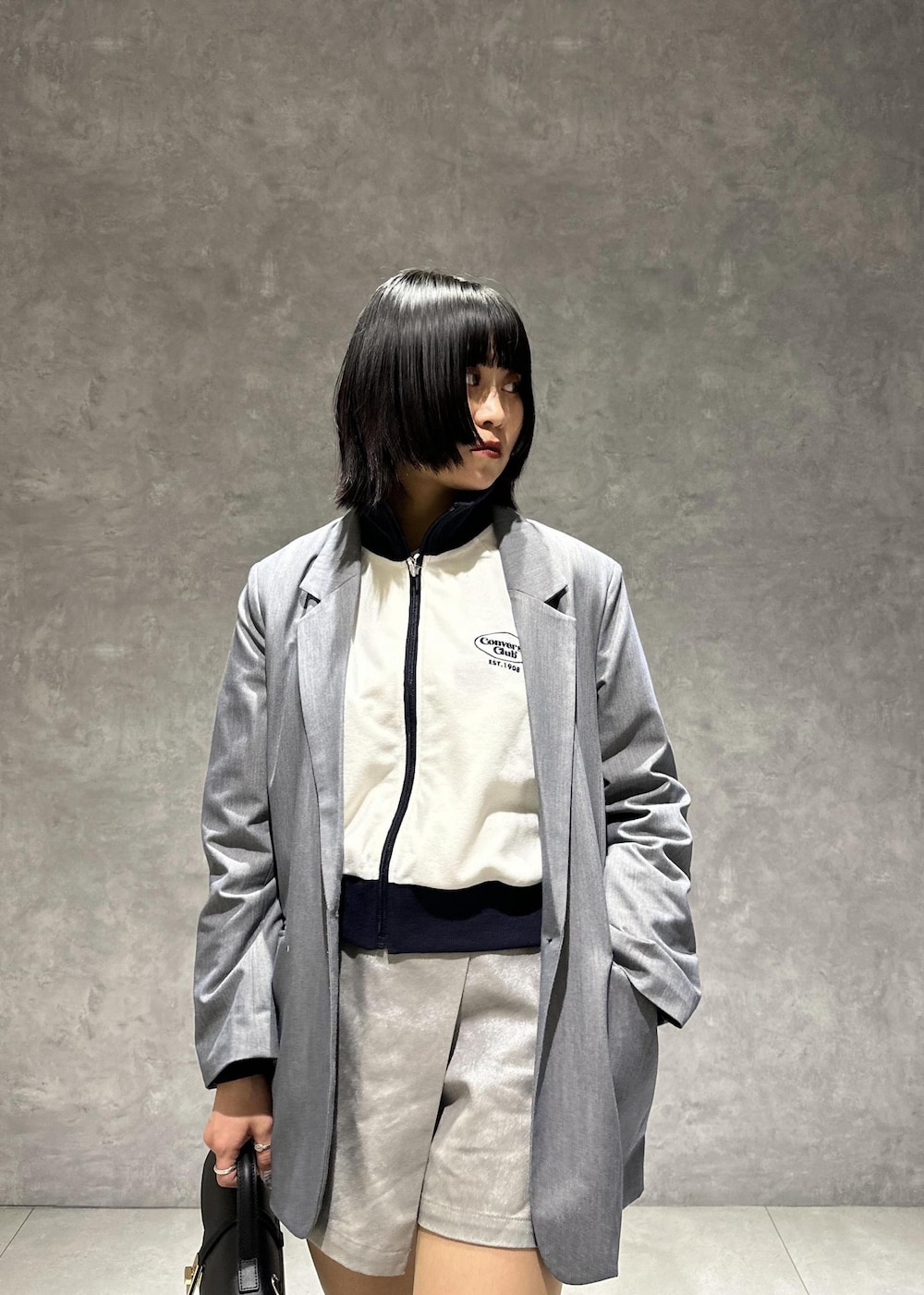 シルバー系のスニーカー、ホワイト系のブルゾン、グレー系のスラックスを着用したレディースの春コーディネートの6枚目の写真
